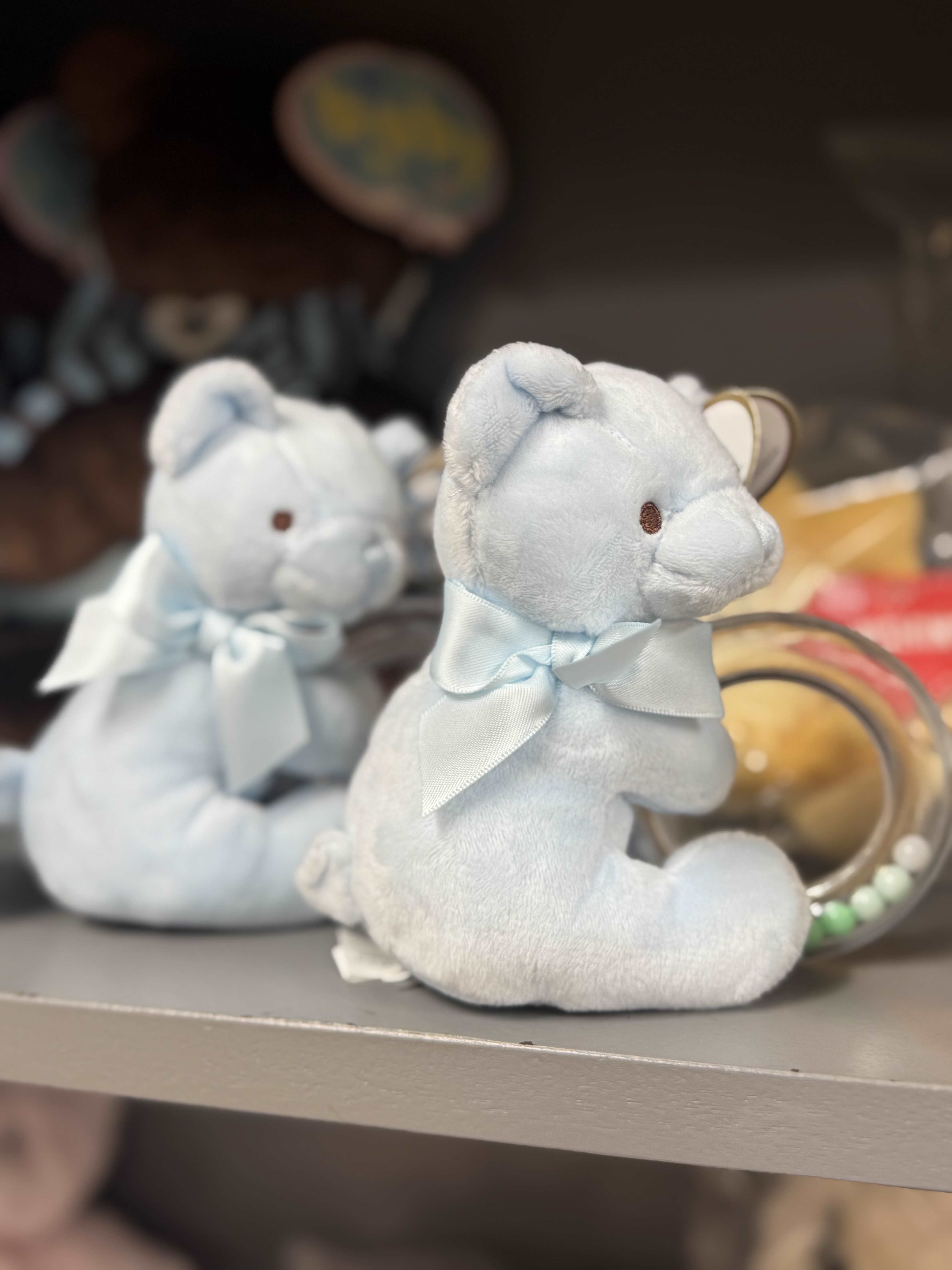 Two light blue teddy bears with ribbons on a shelf