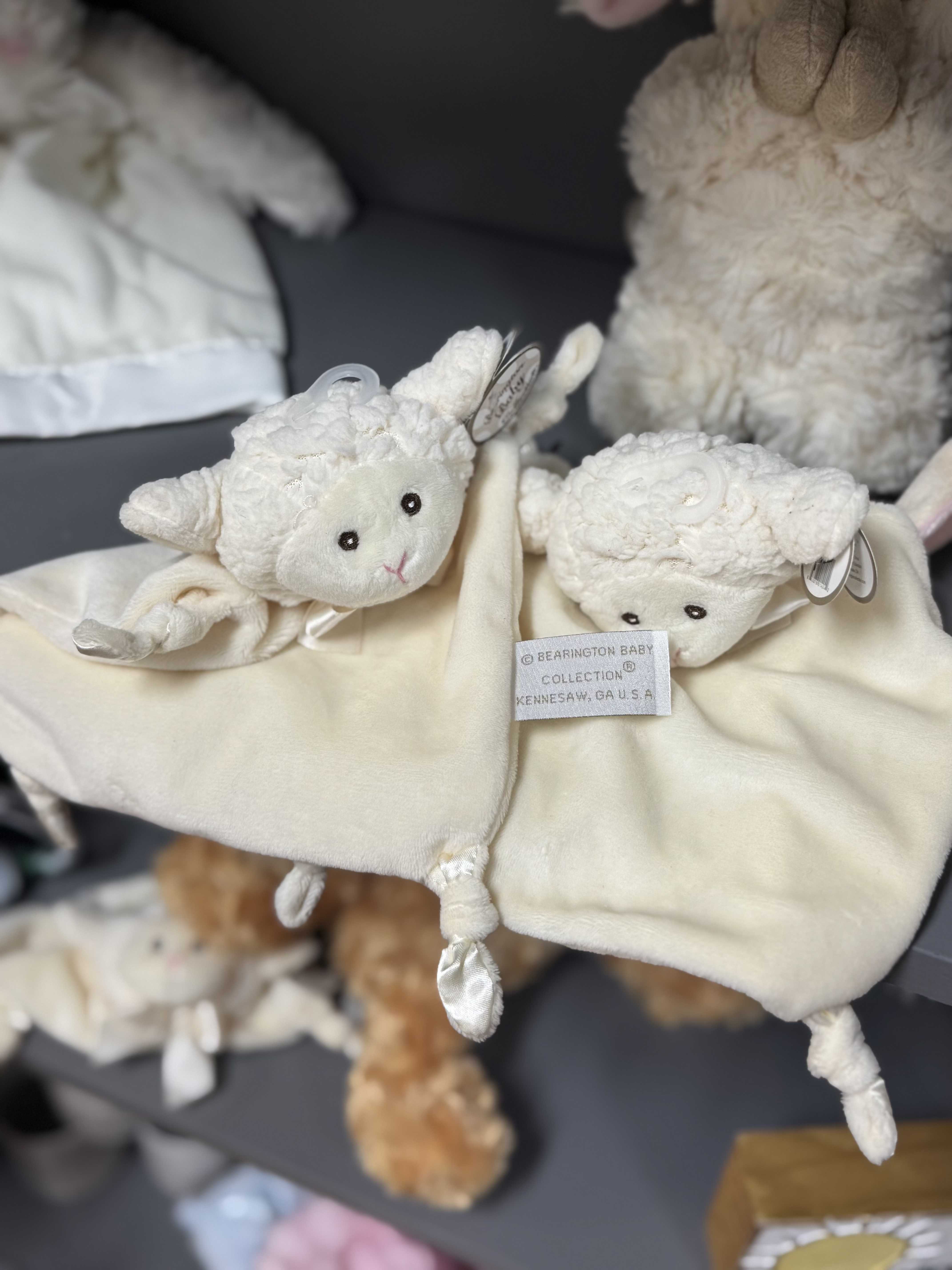 Two cream-colored plush lamb toys with a blanket