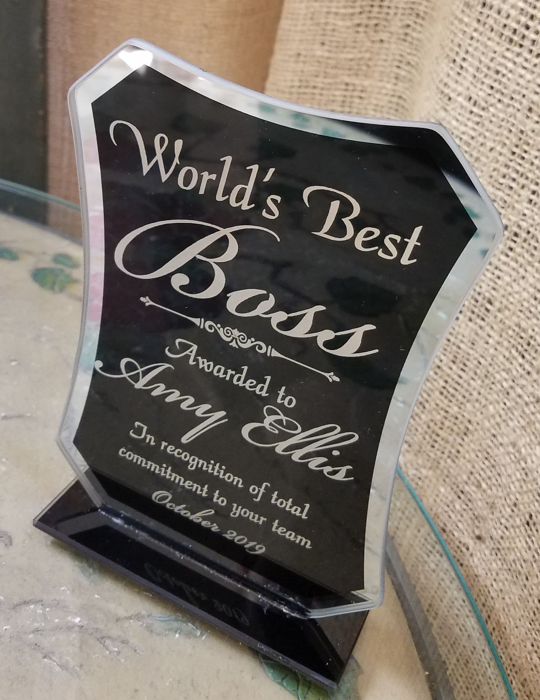 Black acrylic award plaque with silver lettering on a clear base