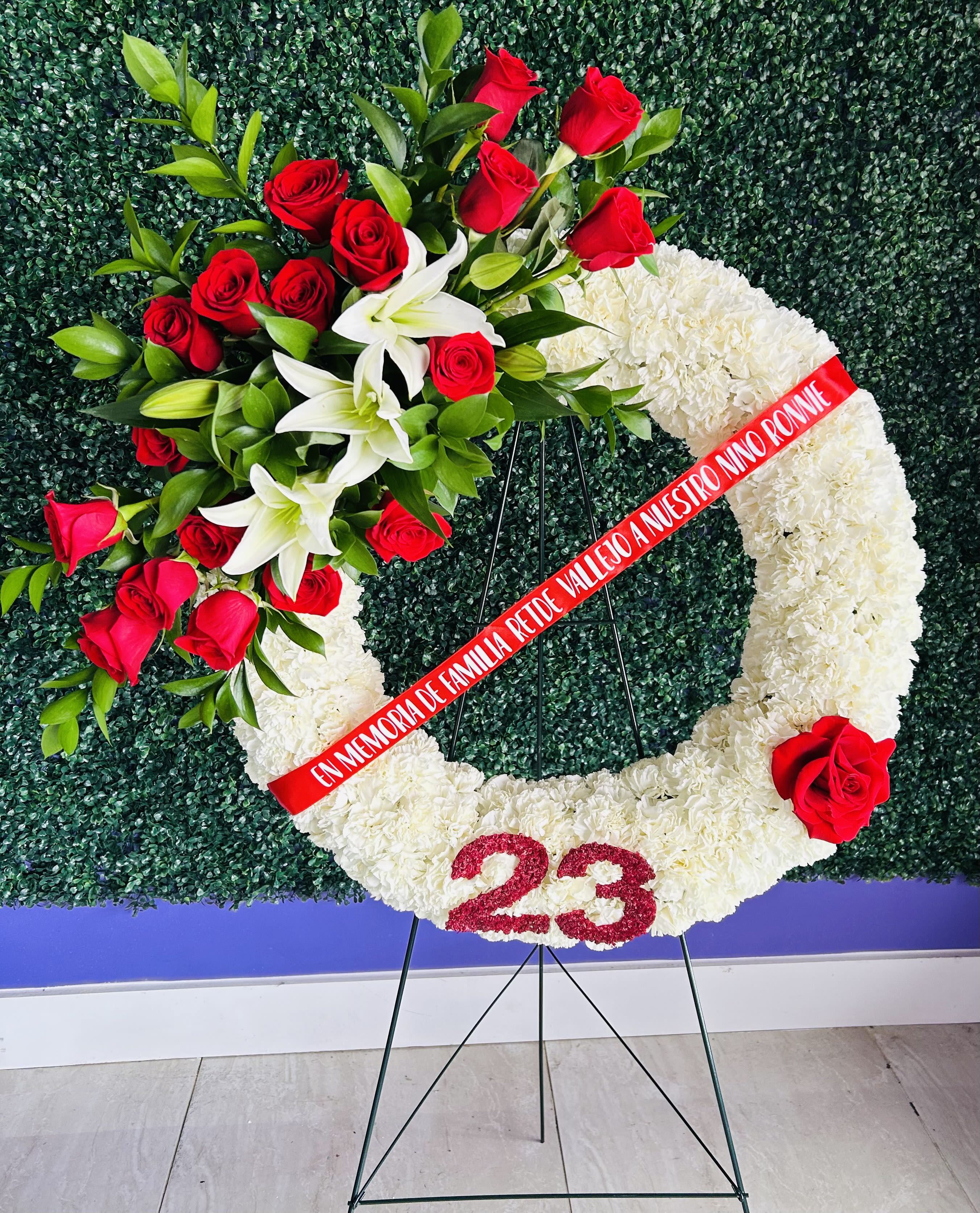 White floral funeral wreath with red roses and lilies on a stand