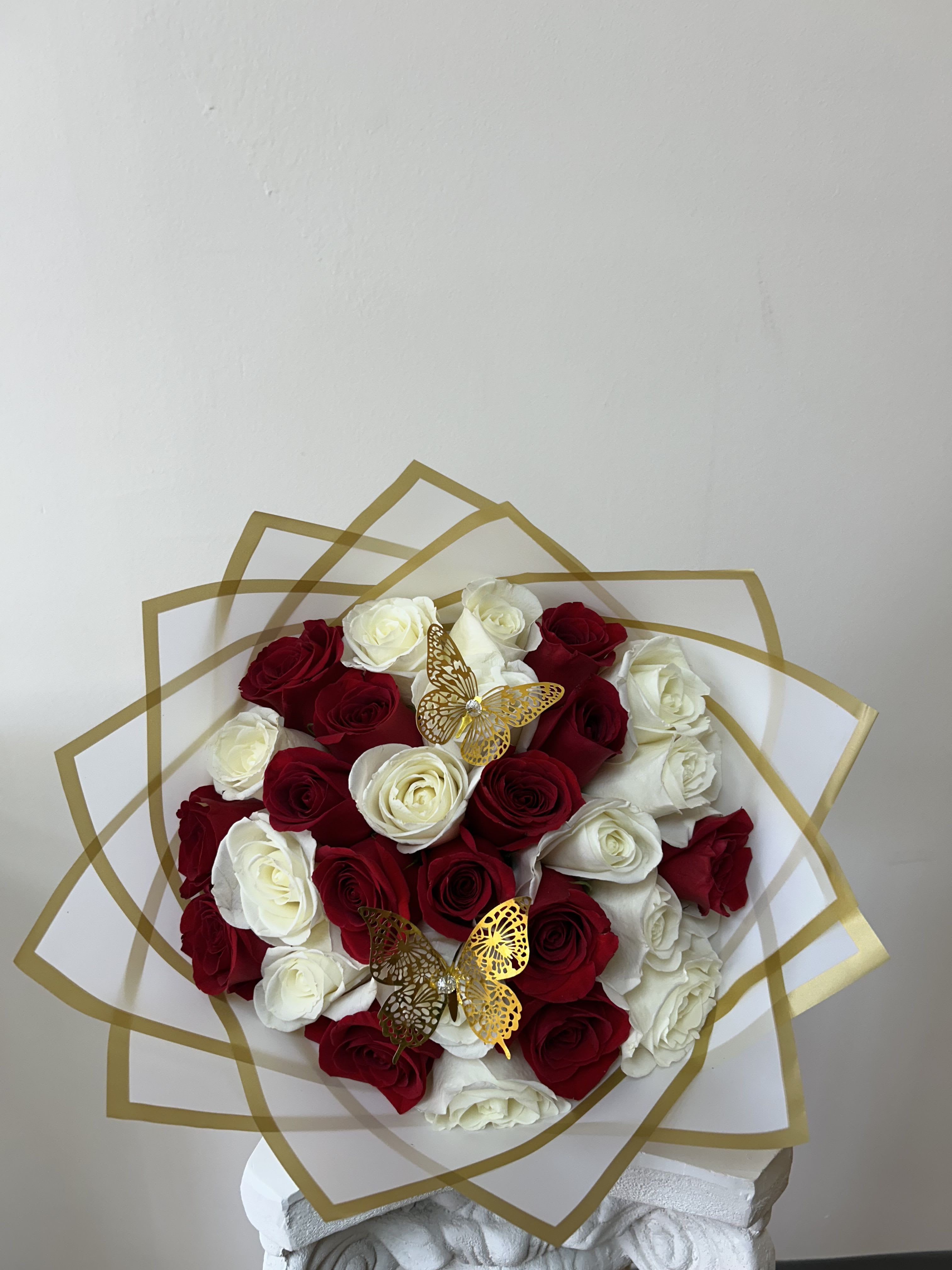 Bouquet of red and white roses with gold butterfly accents