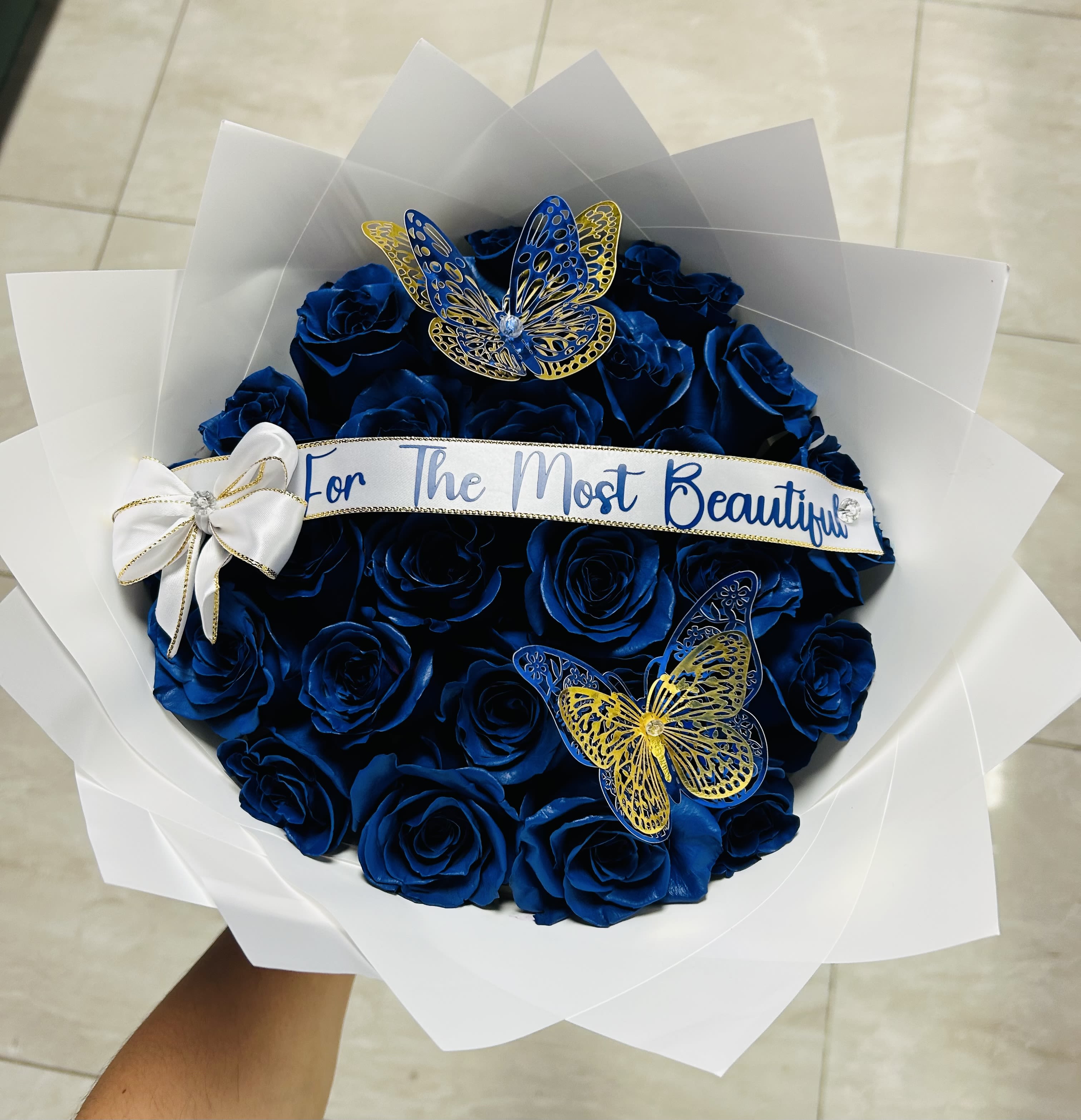 Bouquet of blue roses with butterfly decorations and a ribbon banner