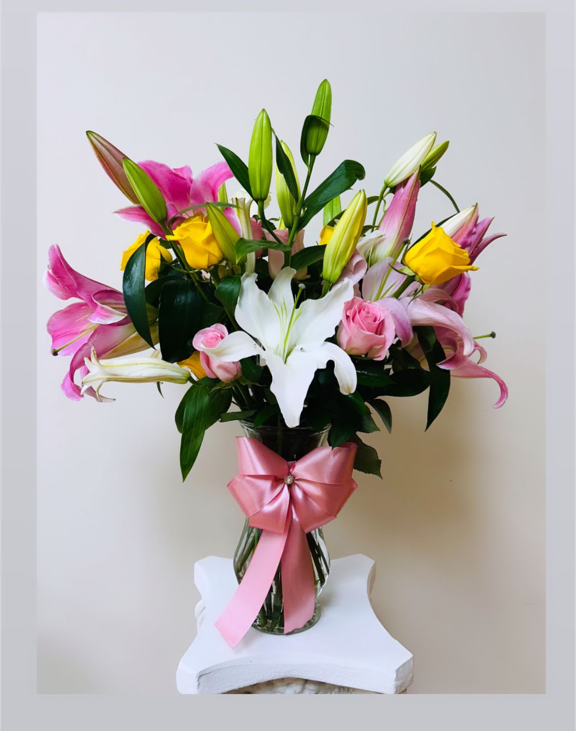 Bouquet of pink and white lilies with yellow roses in a glass vase