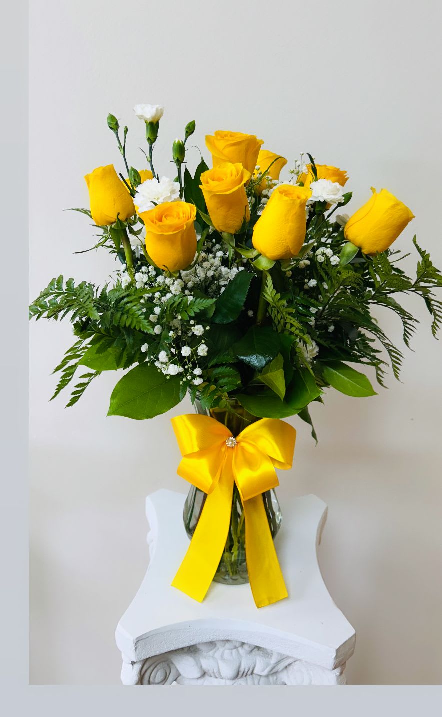 Yellow roses in a glass vase with a yellow ribbon
