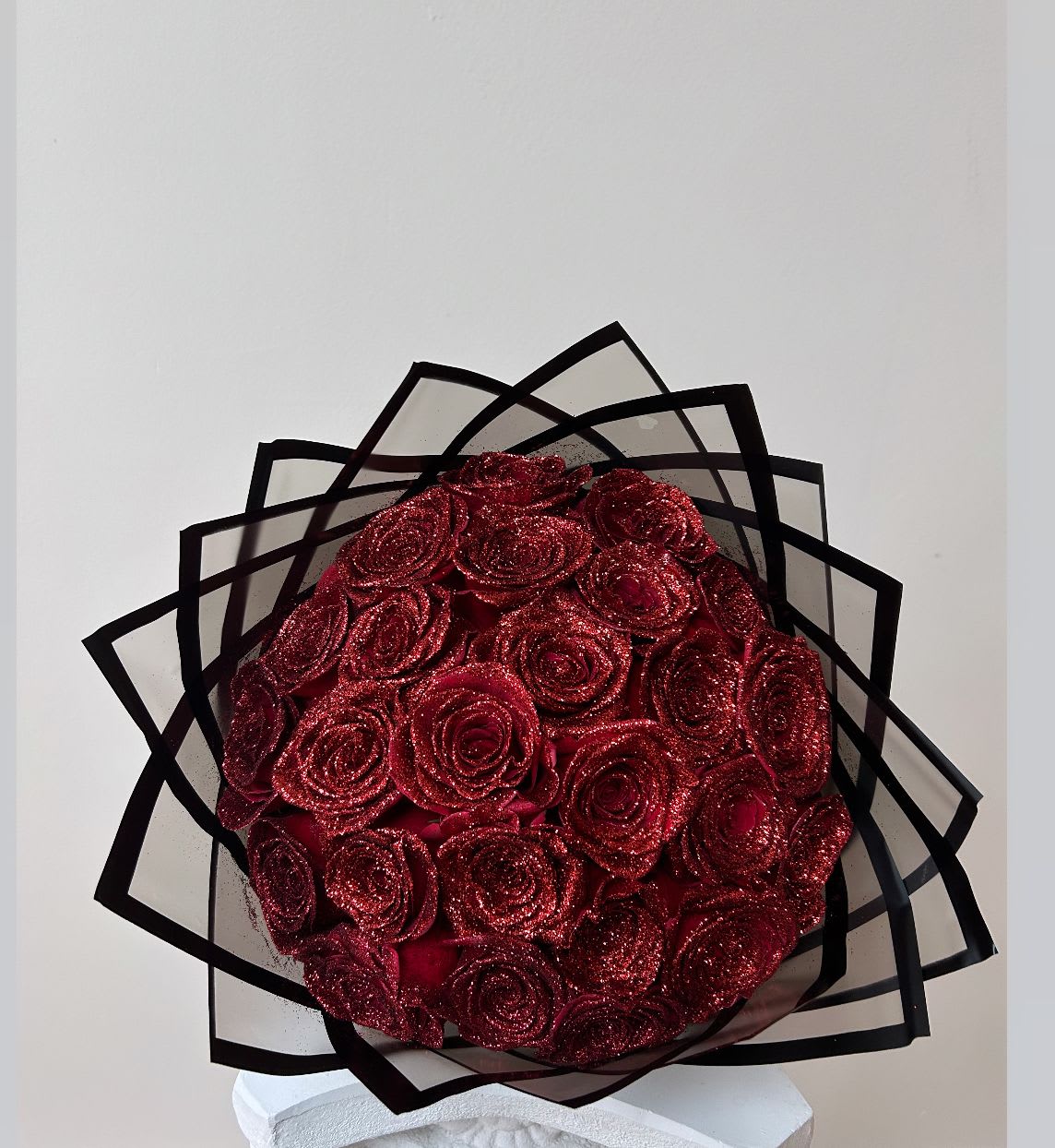 Bouquet of glittery red roses wrapped in black-edged paper