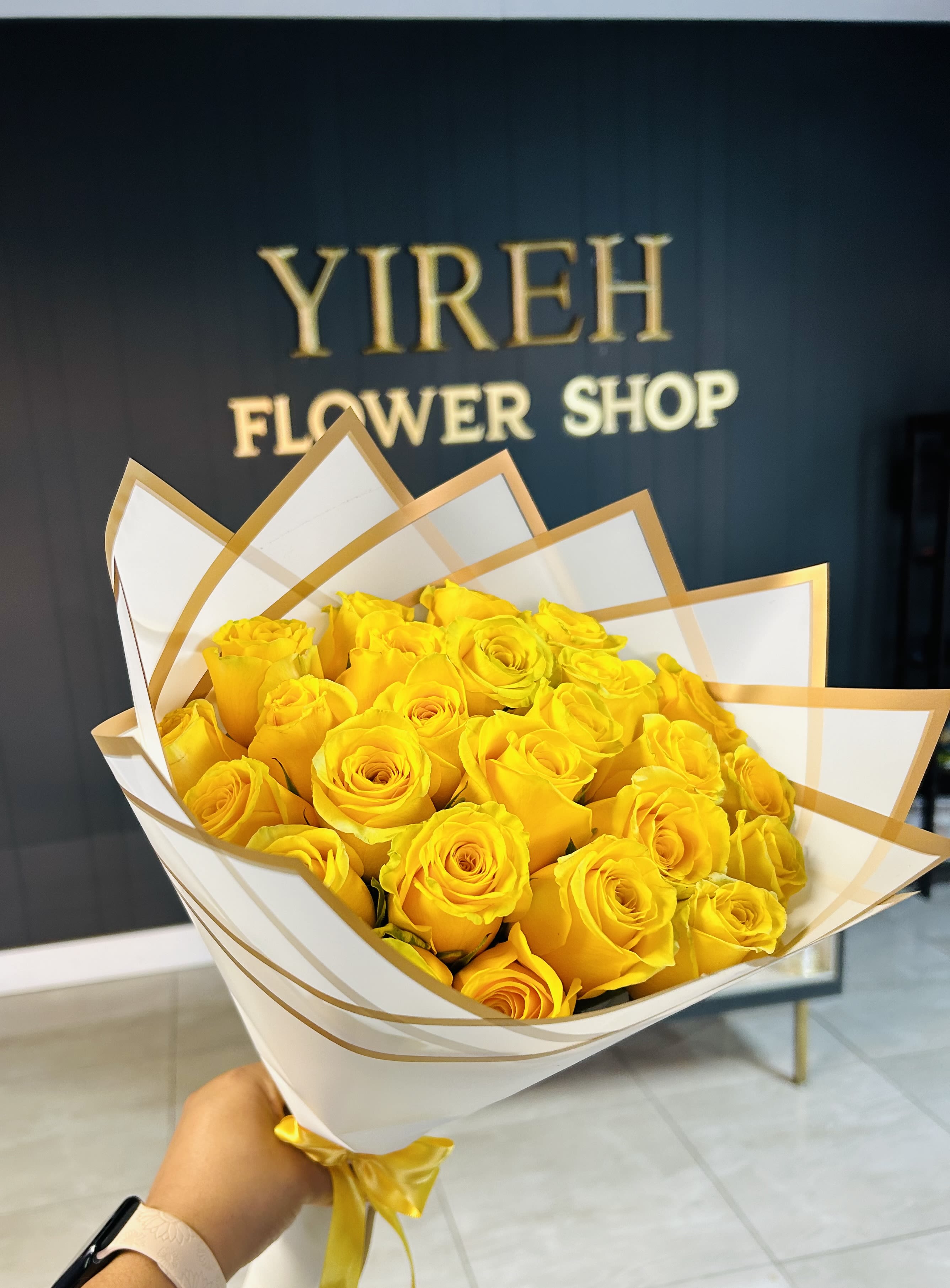 Bouquet of yellow roses wrapped in white and gold paper