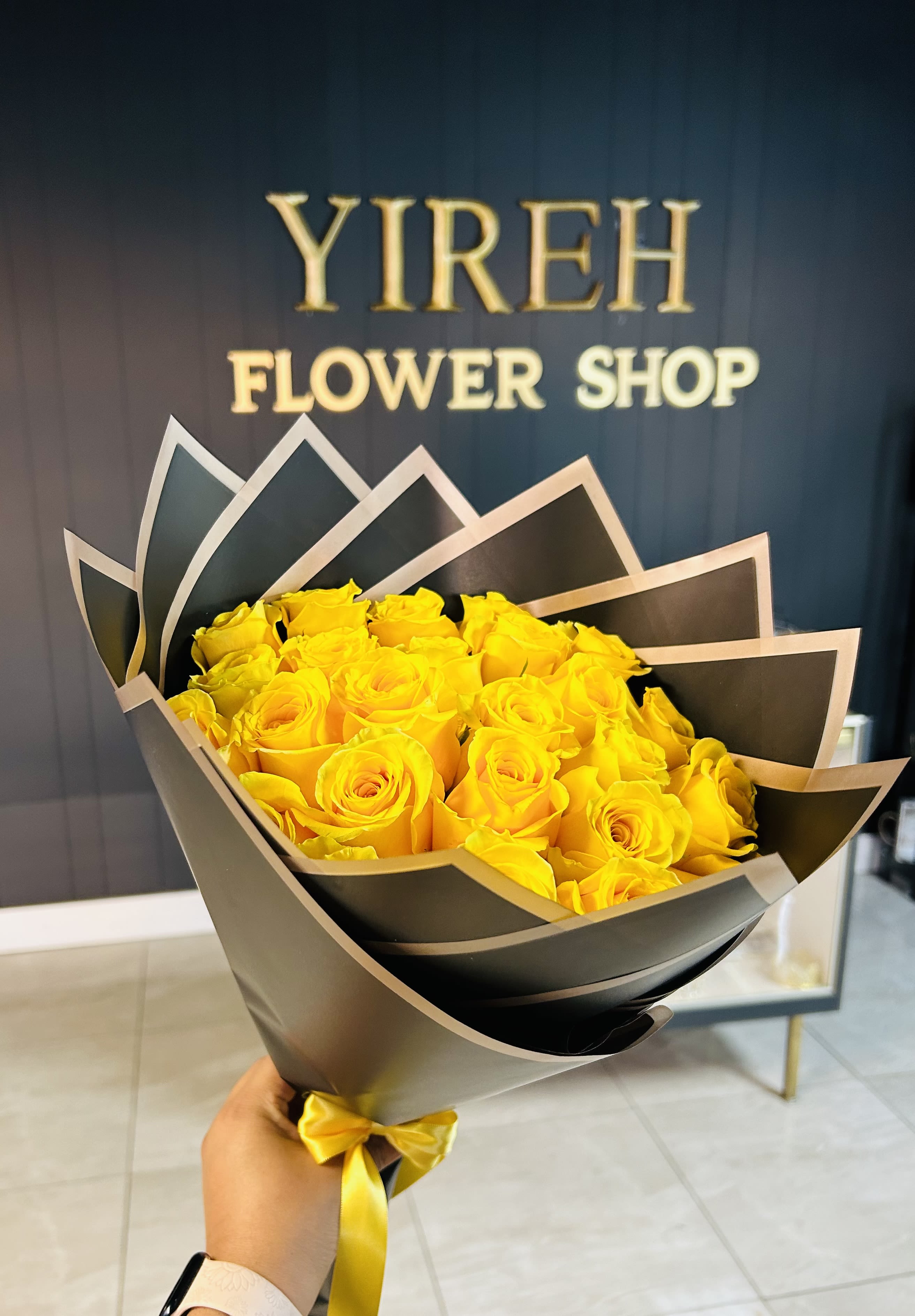 Bouquet of yellow roses wrapped in black paper with a yellow ribbon