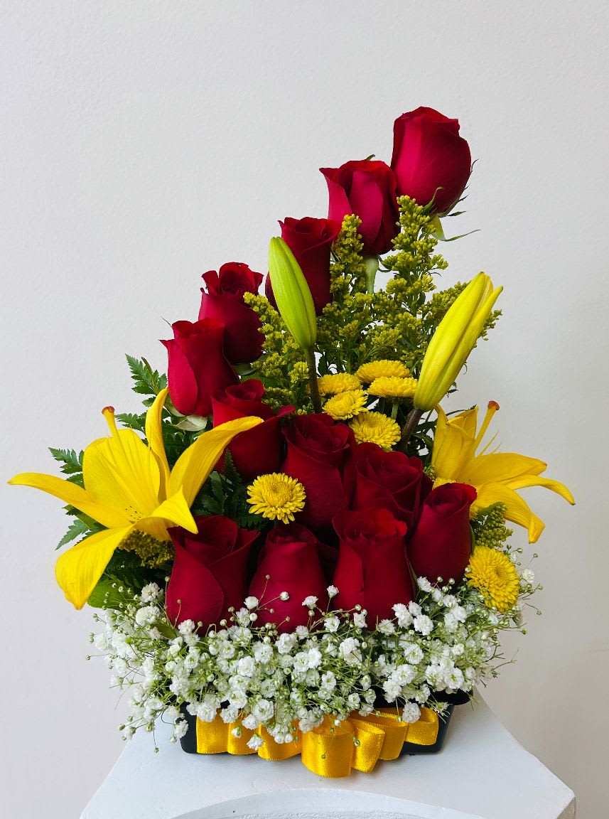 Red roses and yellow lilies arranged in a black container with white filler flowers.