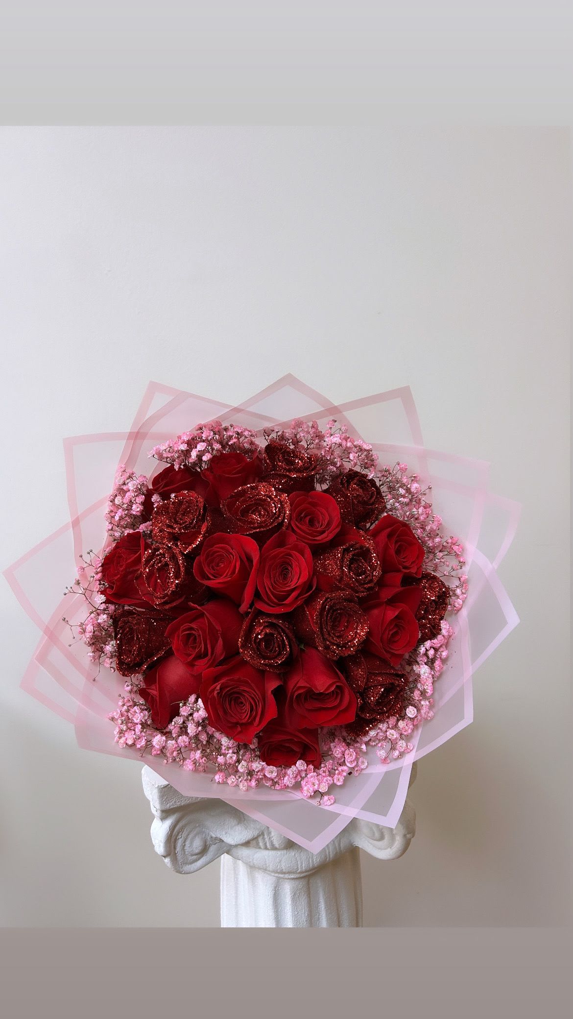 Bouquet of red roses with pink baby's breath and translucent pink wrap