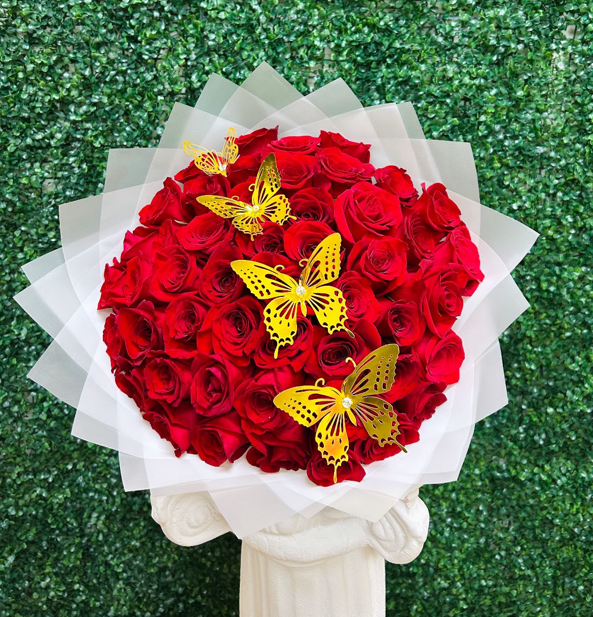 Round bouquet of red roses with yellow butterfly accents