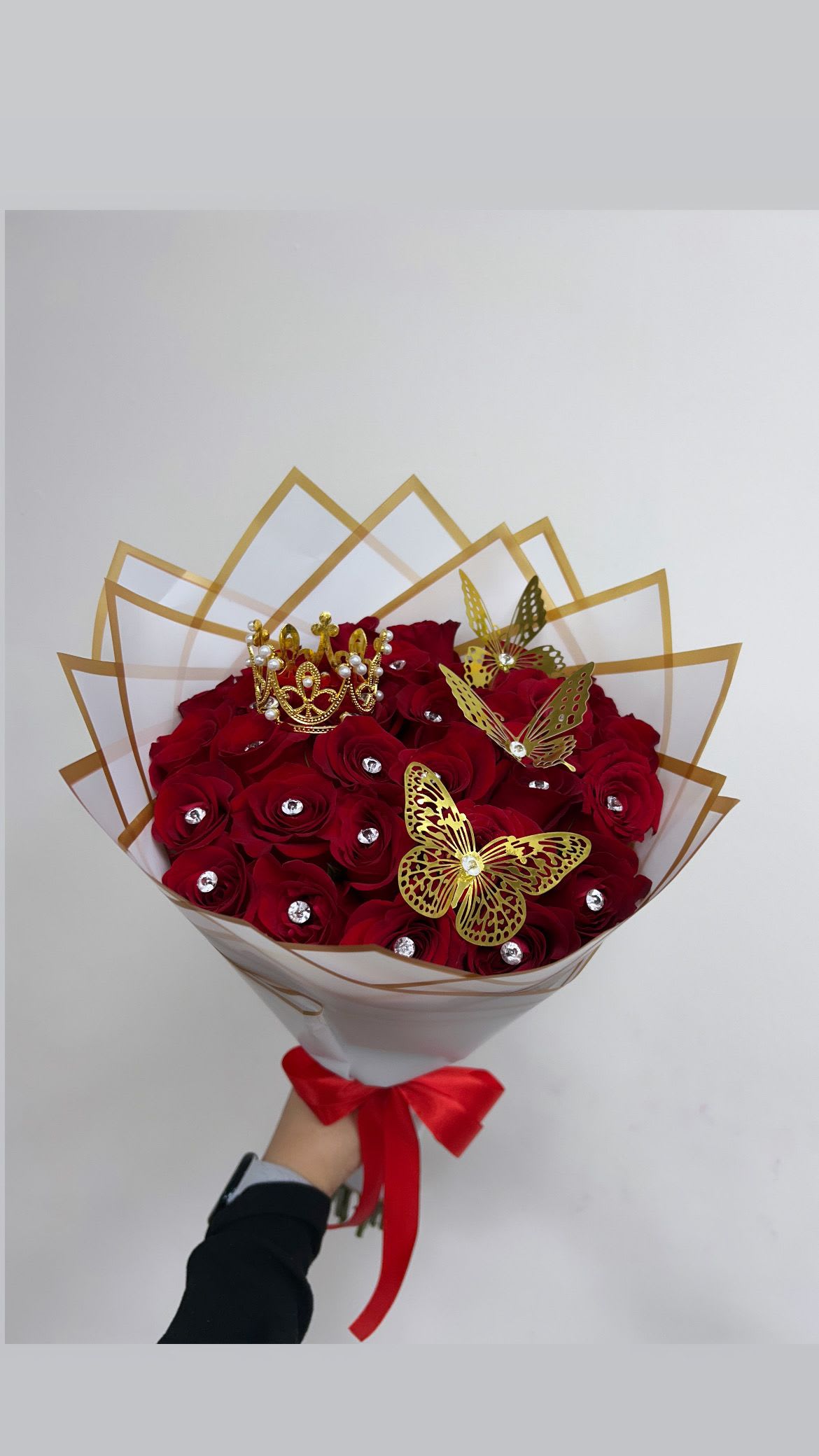 Bouquet of red roses with gold butterfly accents and a crown topper