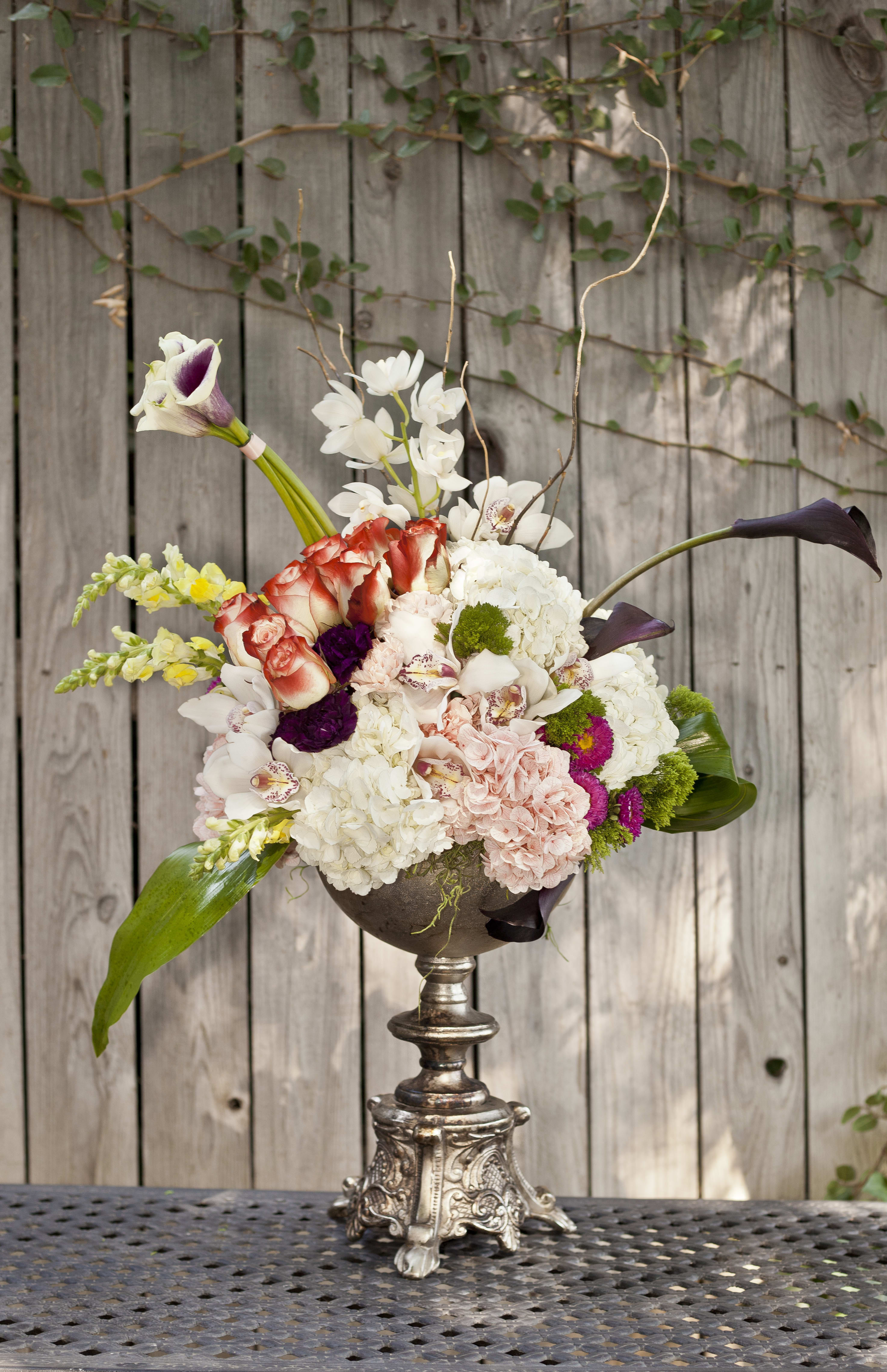 Mixed floral arrangement in a silver pedestal vase with white, pink, and purple blooms