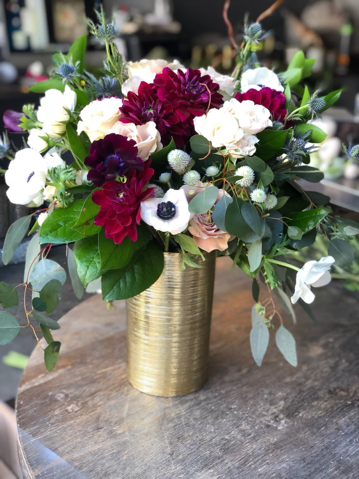 Bouquet of burgundy, white, and blush flowers in a gold vase