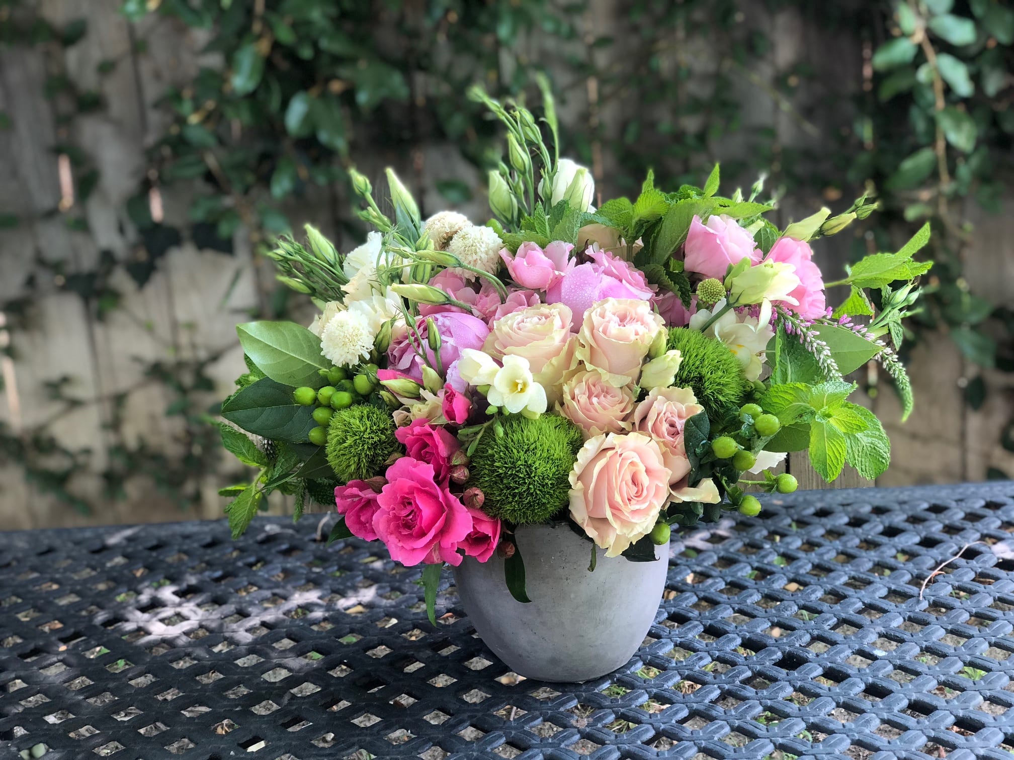 Pink and cream roses in a gray vase with green accents