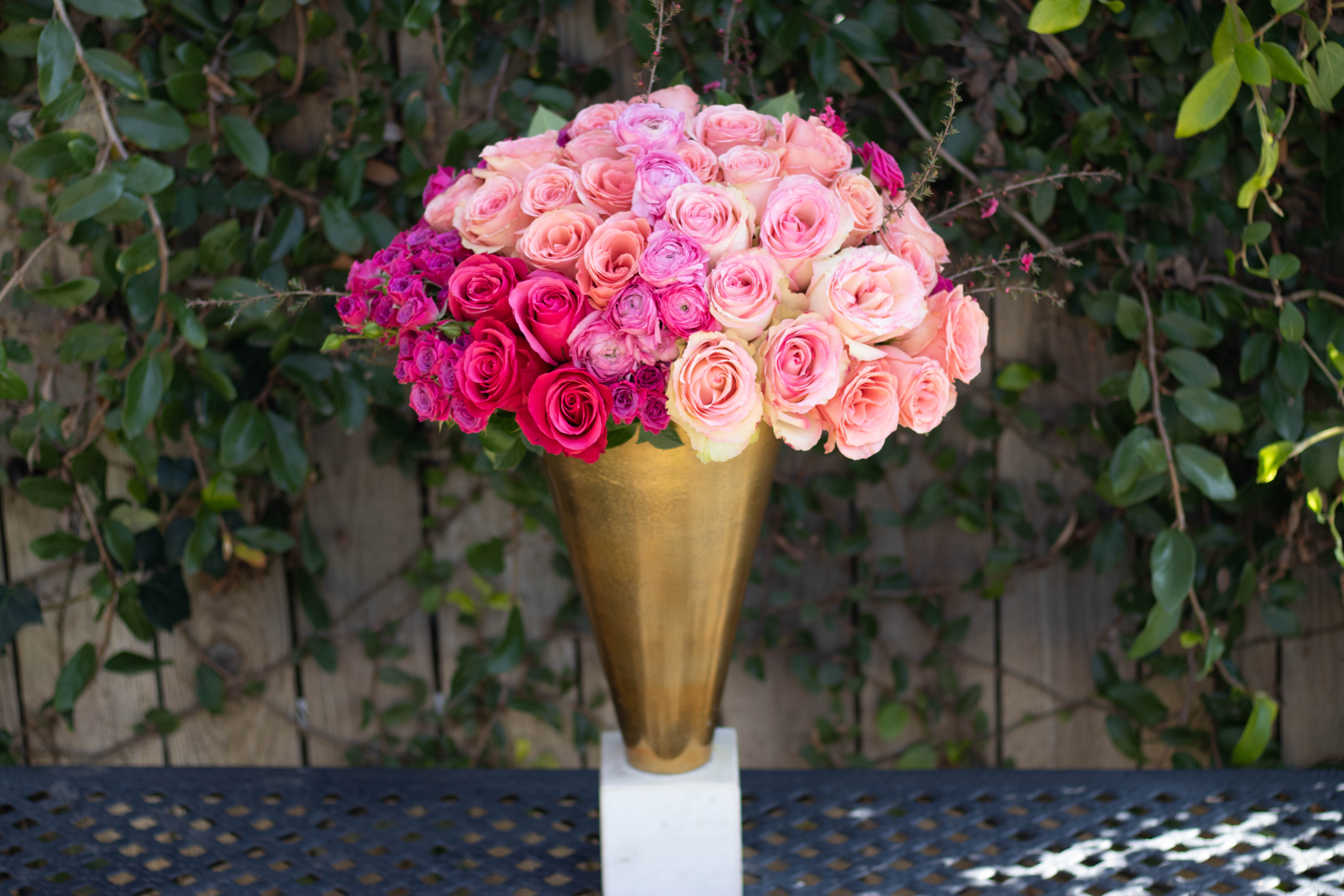 Pink and peach roses arranged in a gold vase