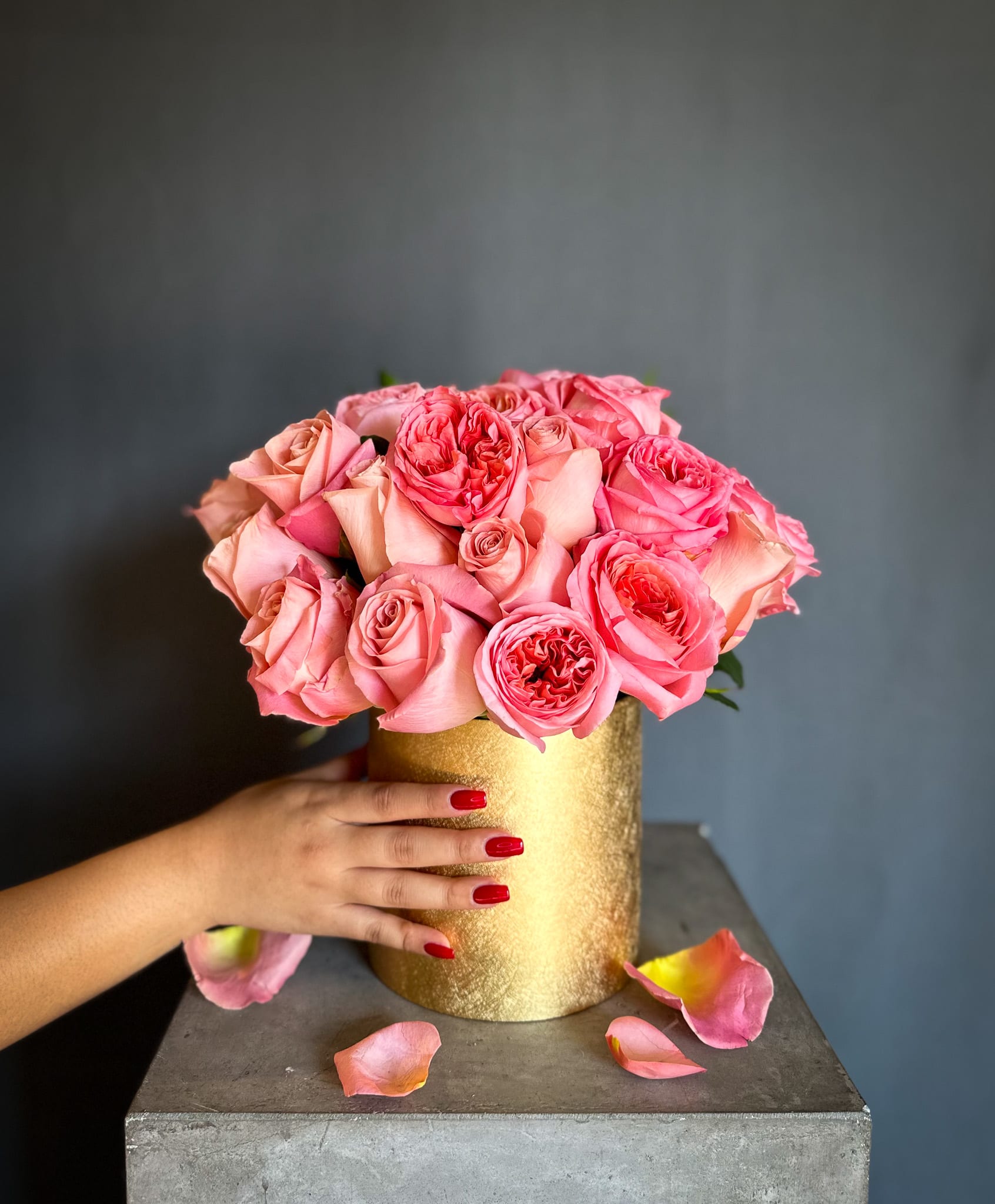 Pink roses arranged in a gold cylindrical vase