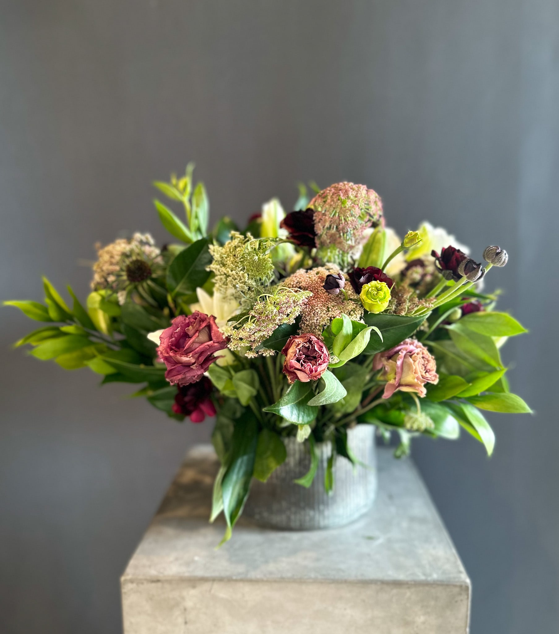 Mixed bouquet in a ribbed metal vase with burgundy and pale pink blooms