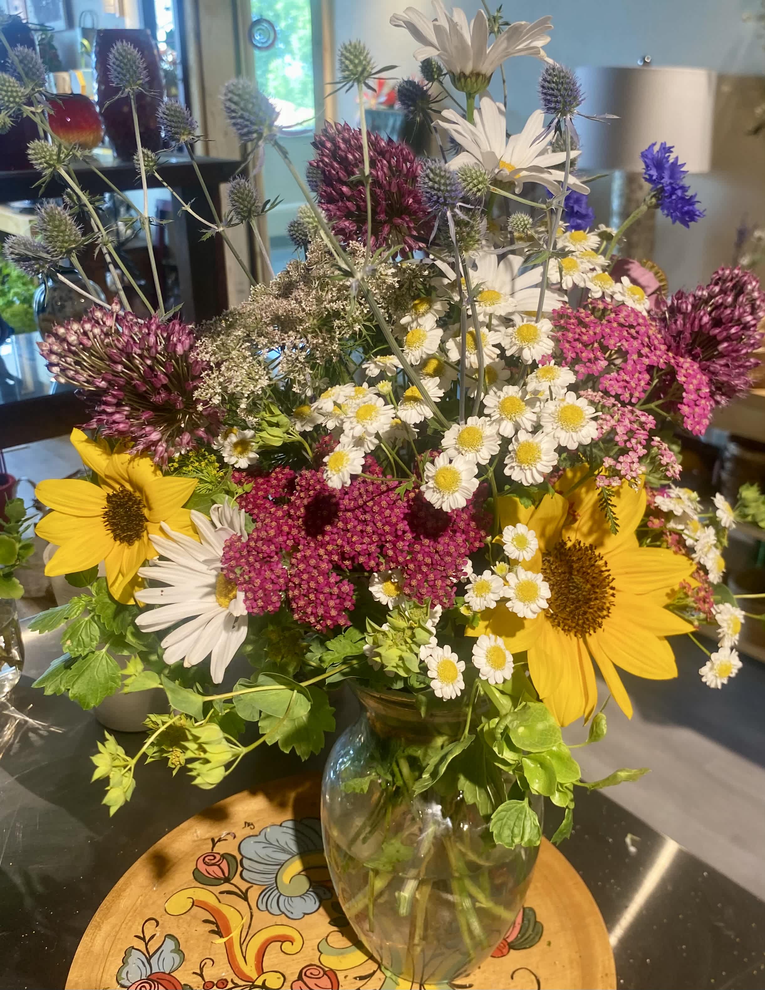 Mixed bouquet with sunflowers, white daisies, and purple allium in a glass vase