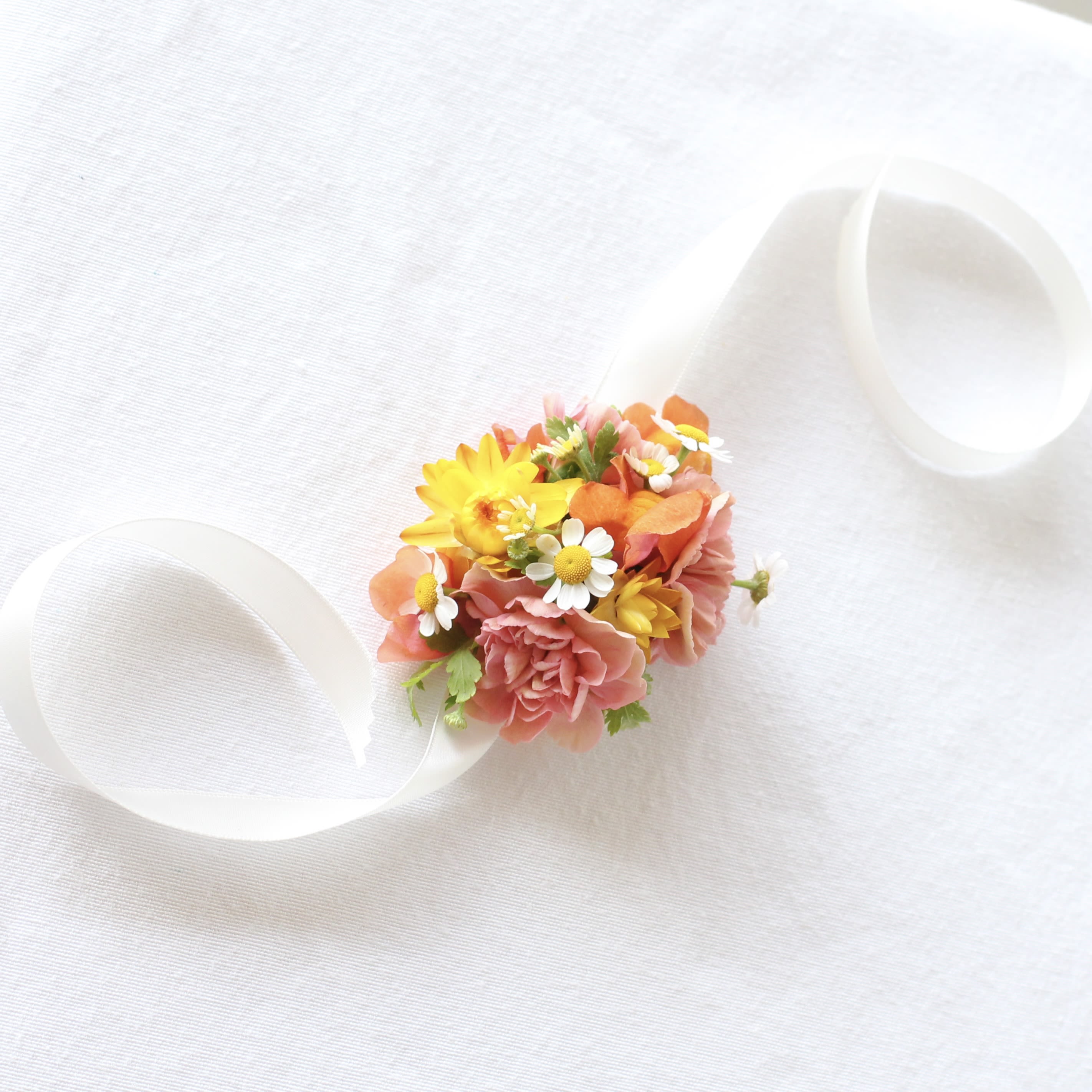 Small bouquet with pink and yellow flowers tied with white ribbon