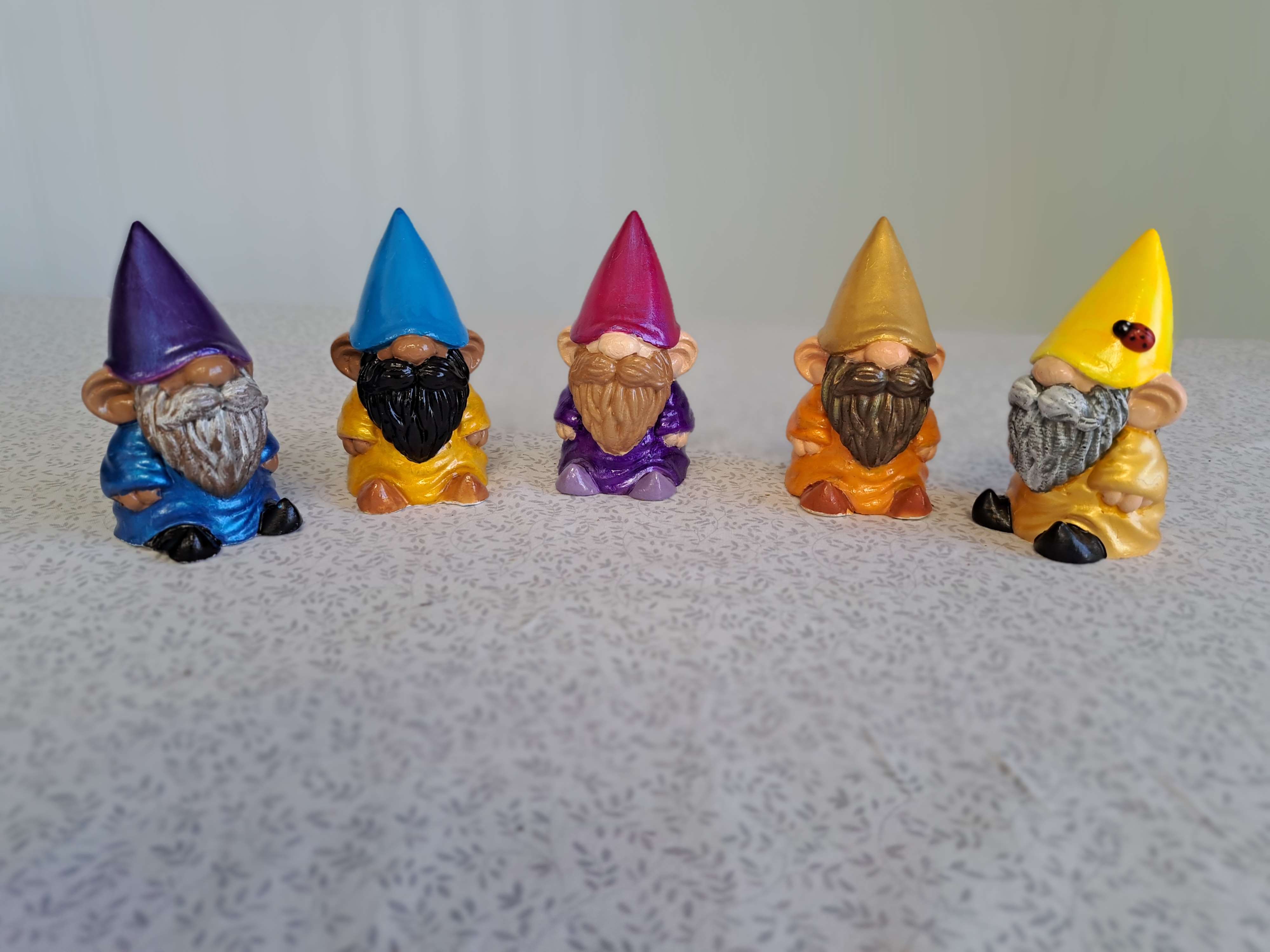 Five small colorful gnome figurines lined up on a tabletop