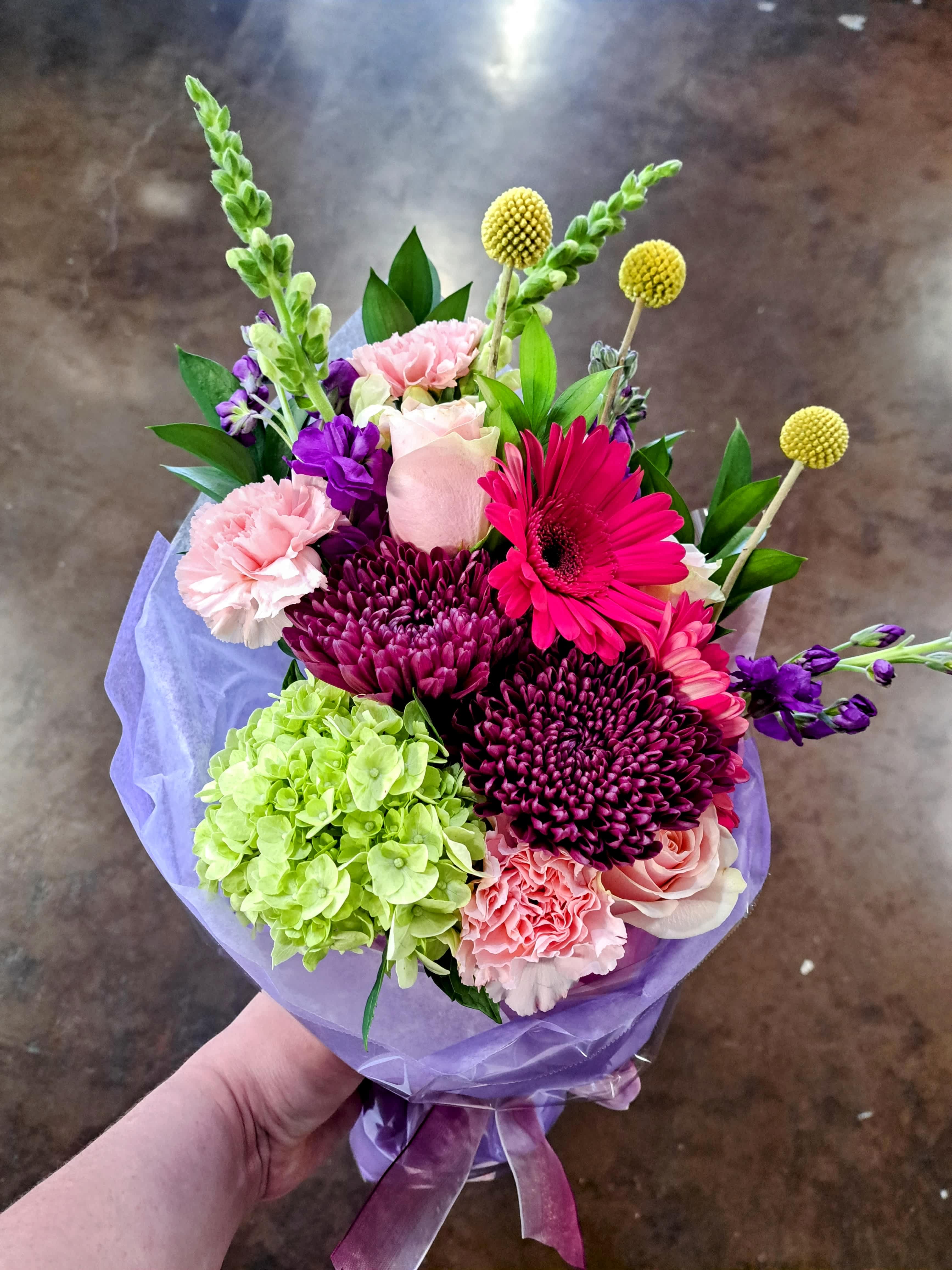 Bouquet of pink, purple, and green flowers wrapped in lavender paper