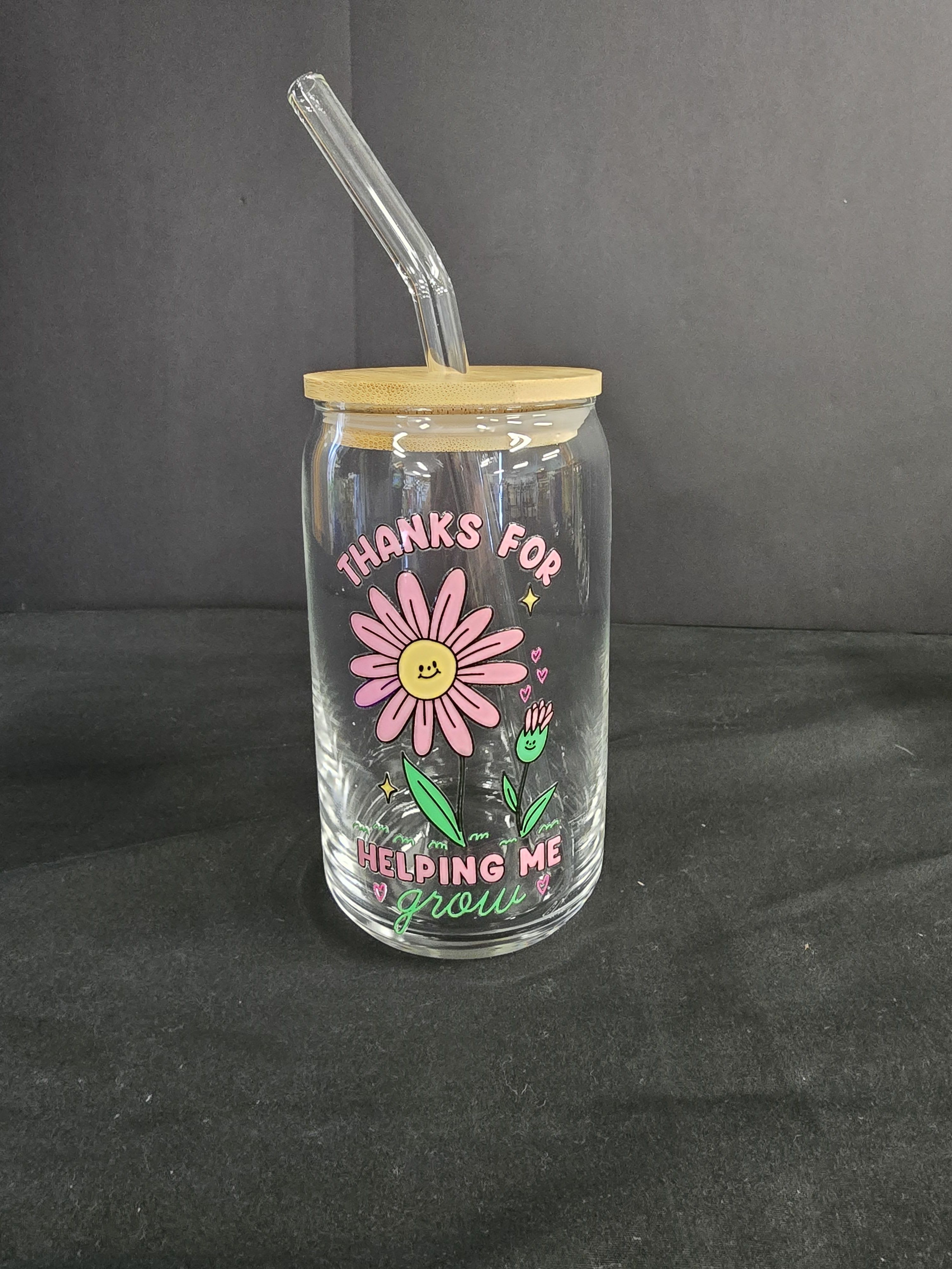 Clear glass tumbler with bamboo lid and straw, decorated with a pink daisy graphic