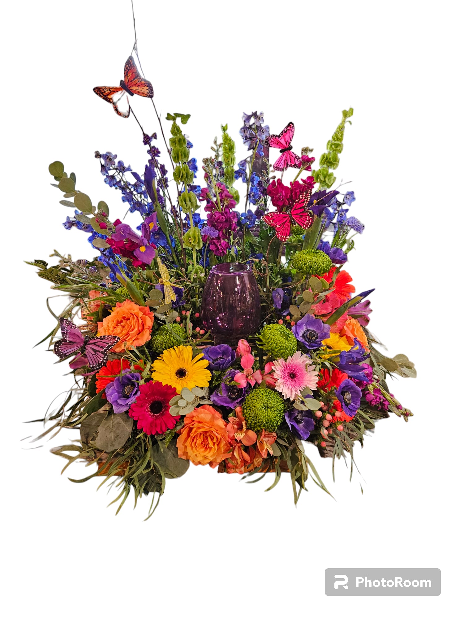 Colorful mixed flower arrangement with butterflies and a purple glass vase