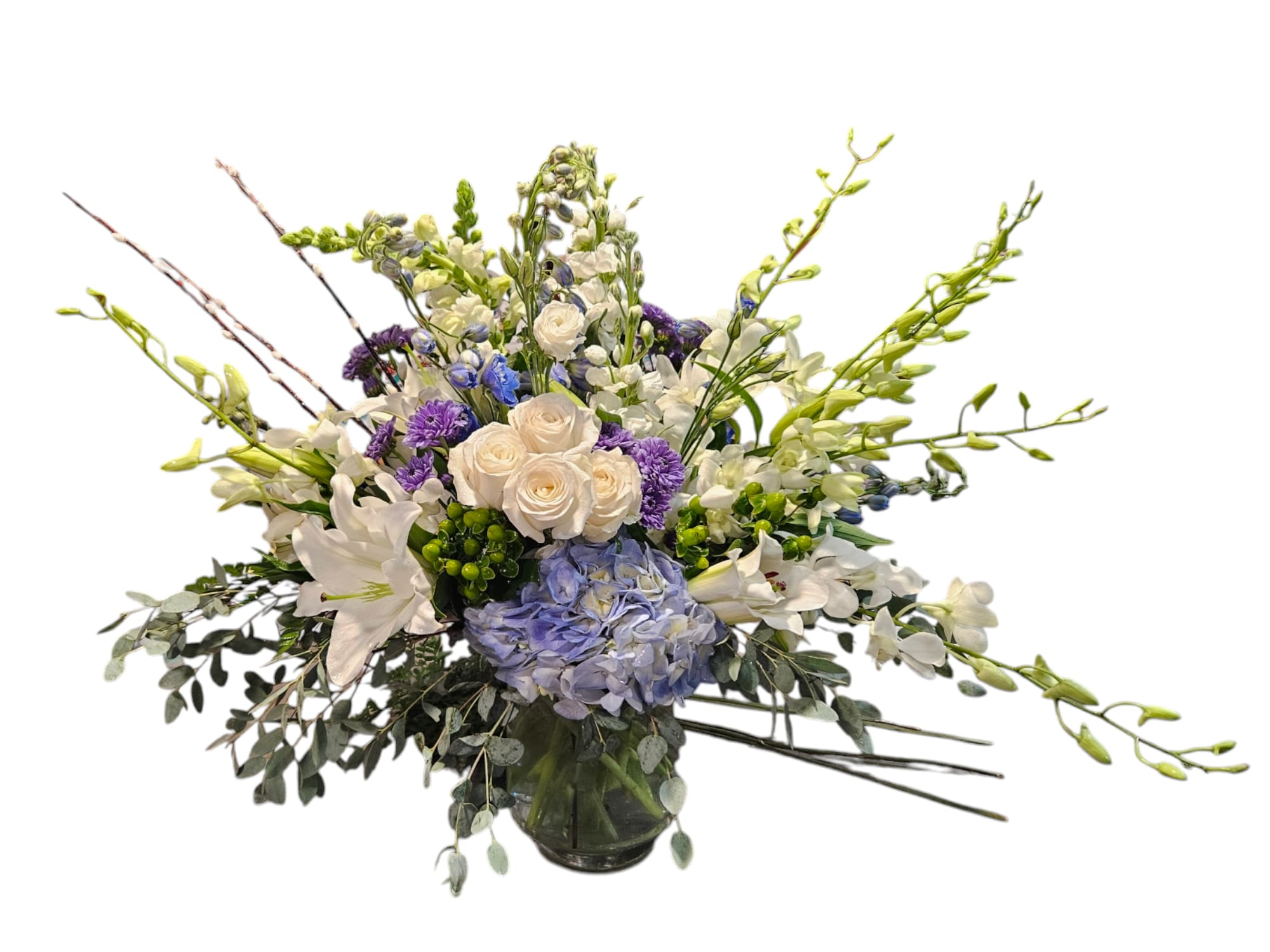 Mixed bouquet of white, blue, and purple flowers in a glass vase