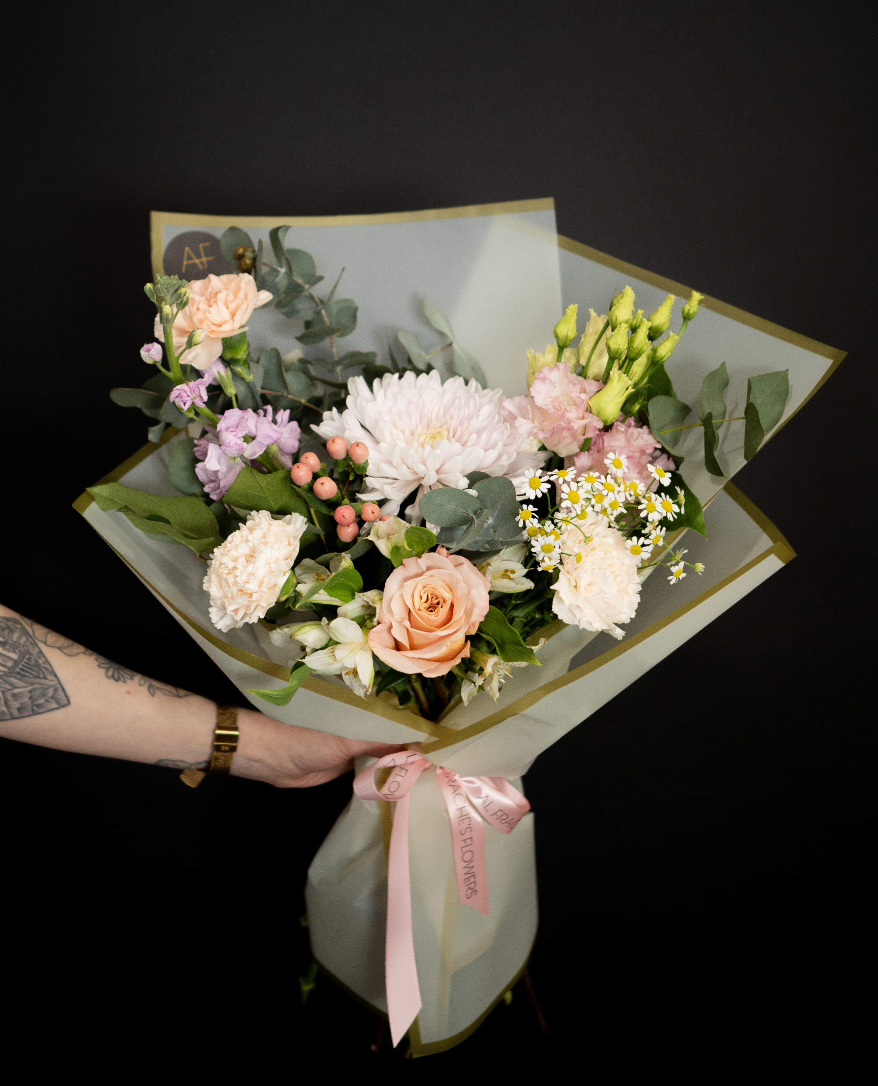 Hand-tied bouquet of peach and white flowers with pink ribbon