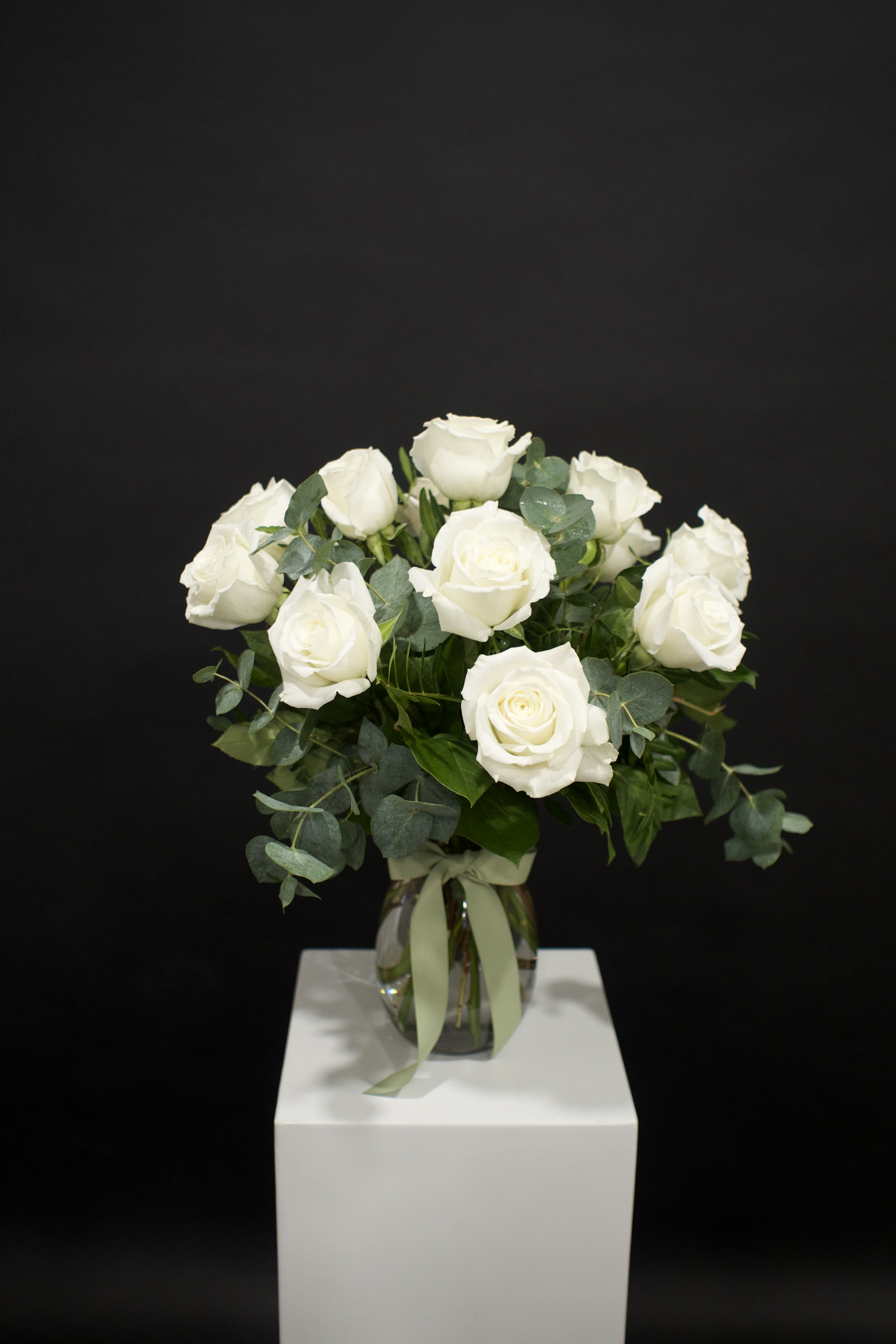 White rose bouquet in a glass vase with ribbon