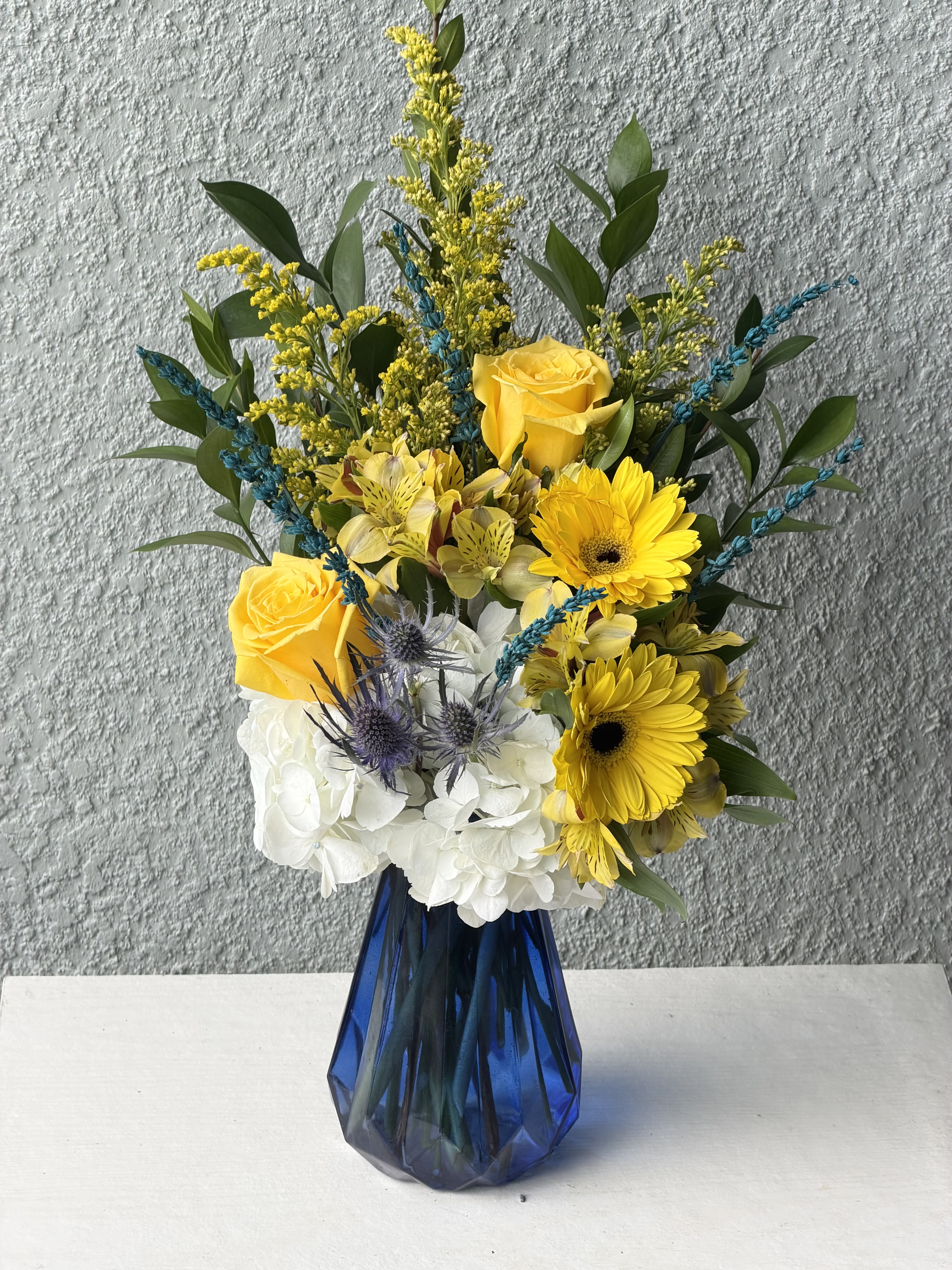 Blue by bliss  - Bright yellow roses and gerbera daisies pop against billowy white hydrangeas and pale alstroemeria in this cheerful flower arrangement-perfect as a birthday bouquet, thank-you gift, or everyday celebration arrangement.