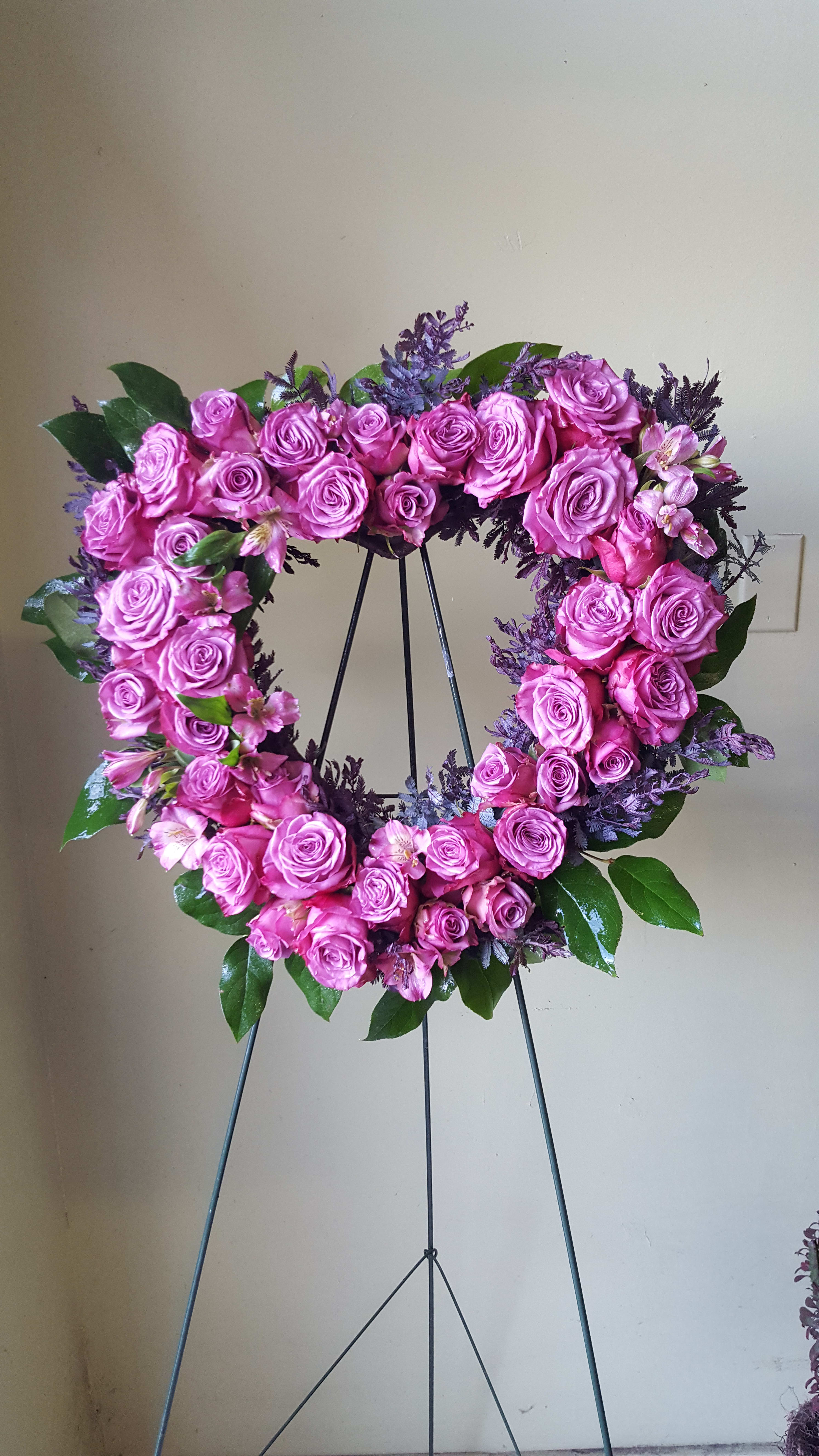 Pink rose wreath on a metal stand with small accent flowers