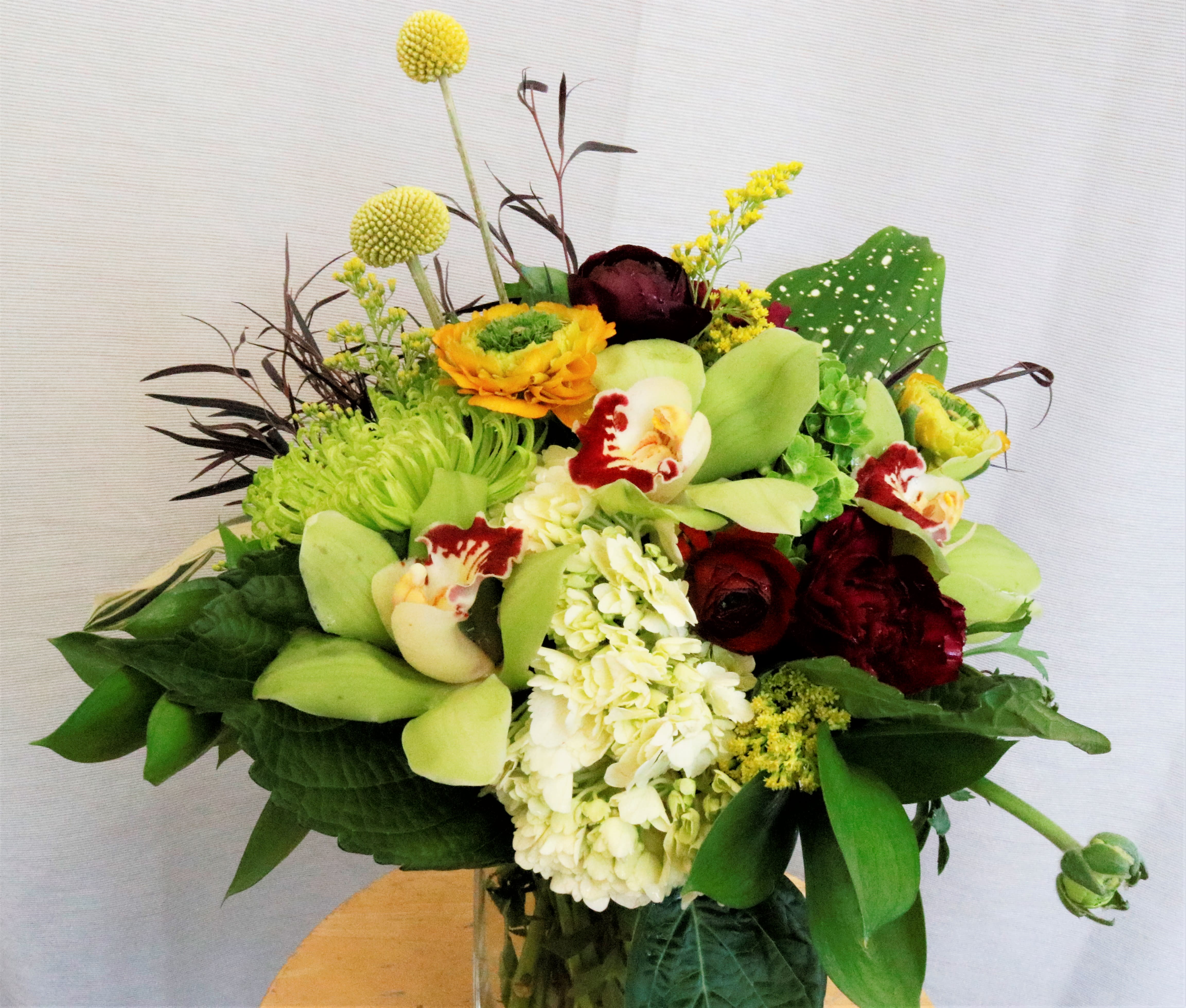 Mixed bouquet with green orchids, white hydrangea, and dark red roses in a vase