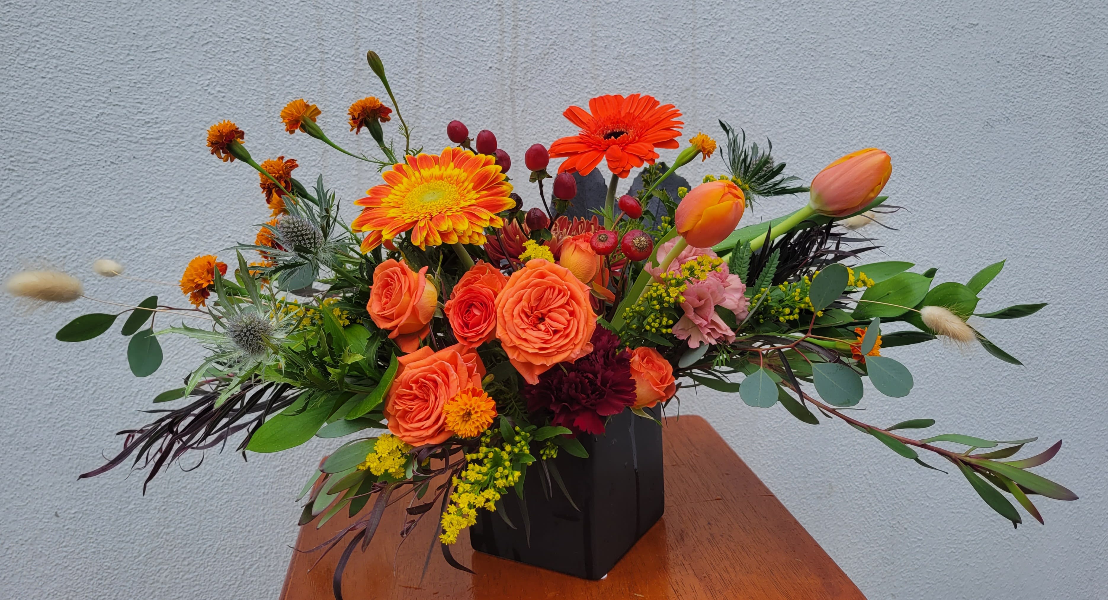 Orange and yellow floral arrangement in a black vase