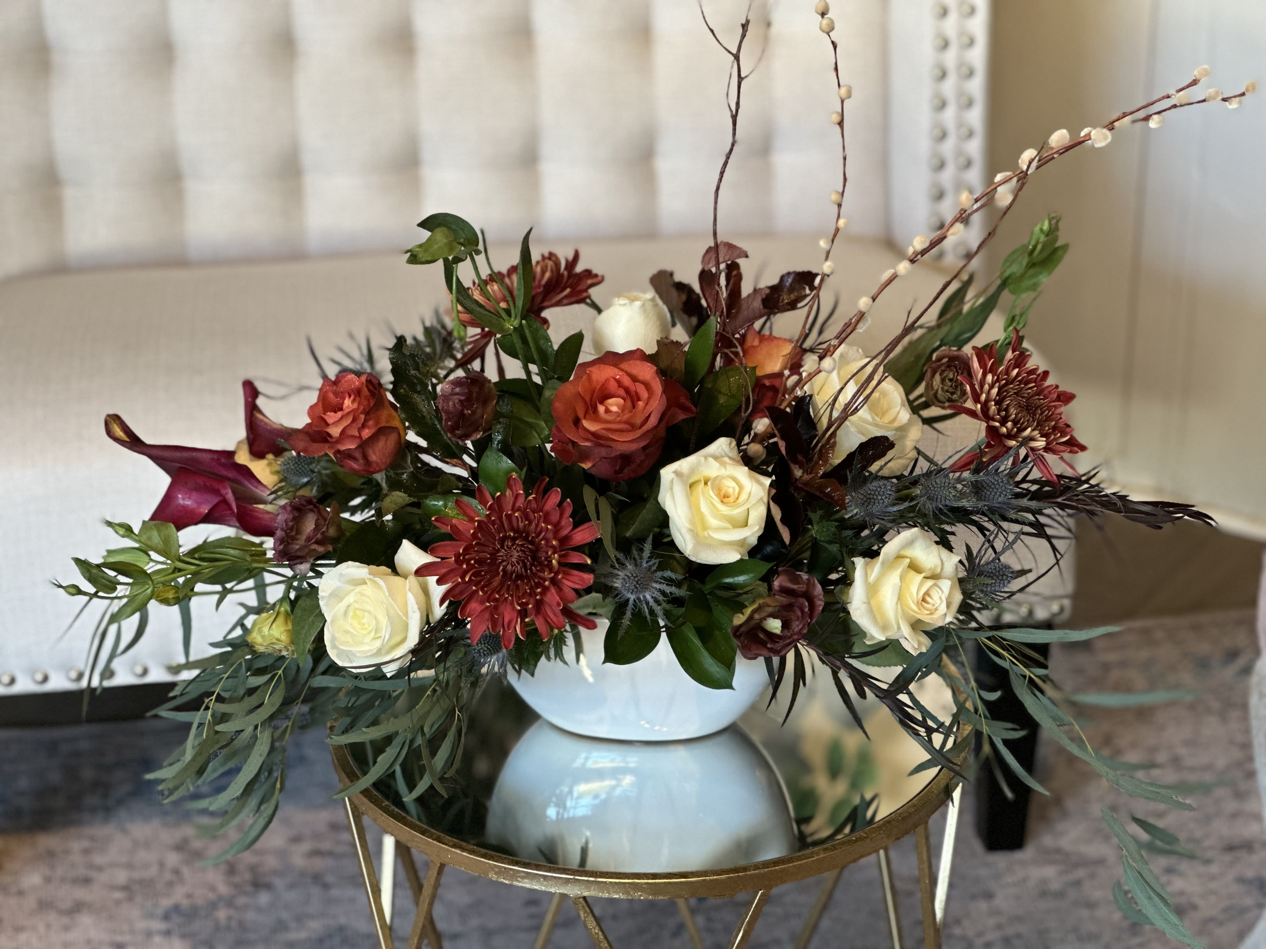 Mixed roses and burgundy flowers arranged in a white vase
