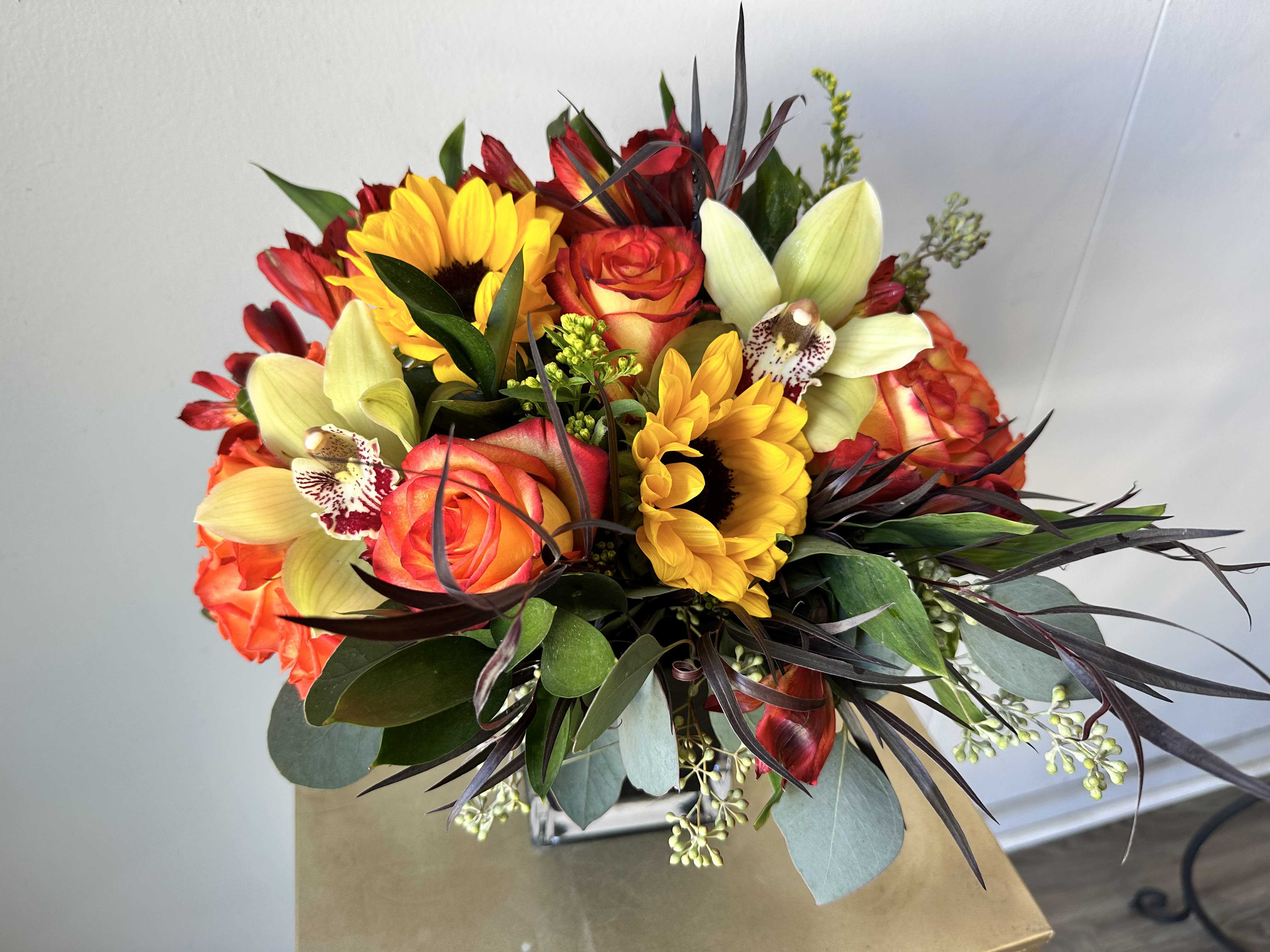 Bouquet with sunflowers, roses, and pale orchids in a vase