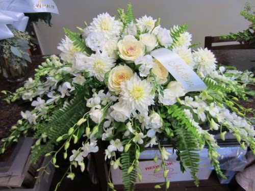 White floral casket spray with cream roses and daisies