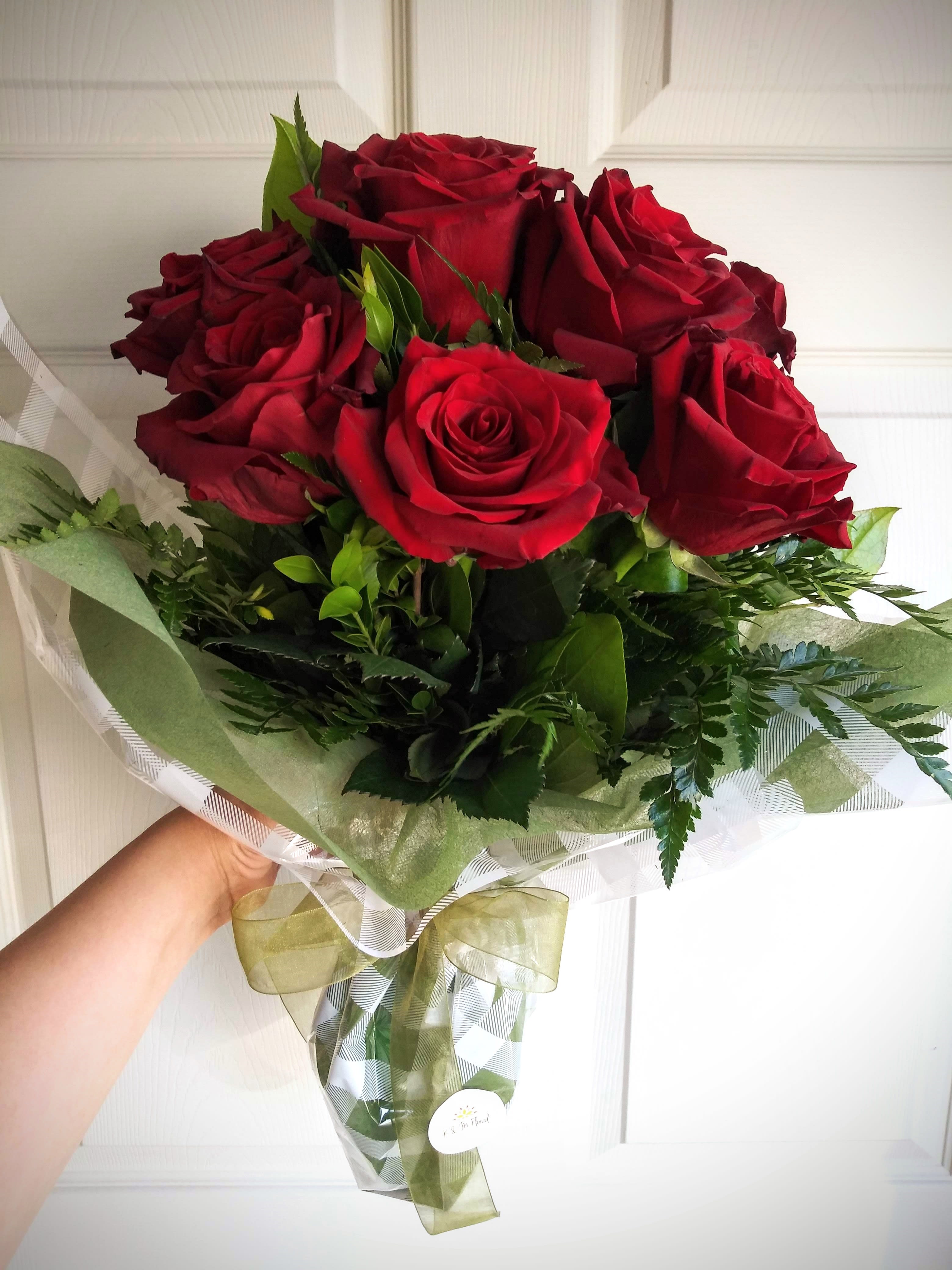 Bouquet of red roses wrapped in green and clear paper