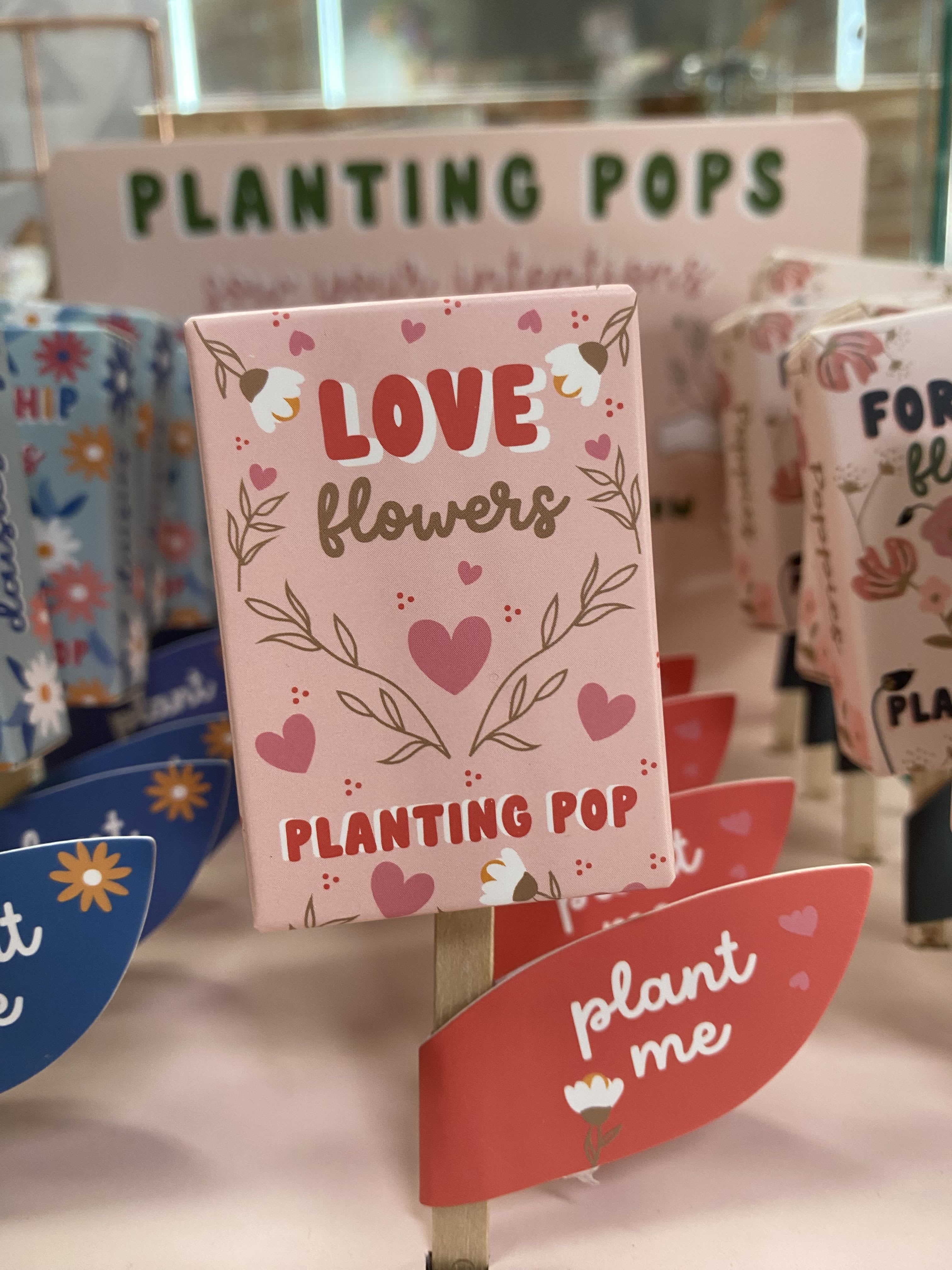 Pink plant marker with hearts and the words "Love flowers"