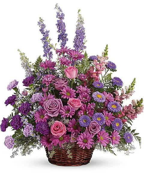 Purple and pink mixed flower arrangement in a wicker basket