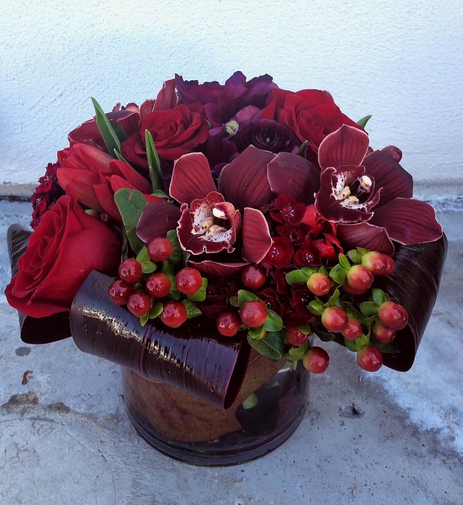Red roses and burgundy orchids in a dark vase