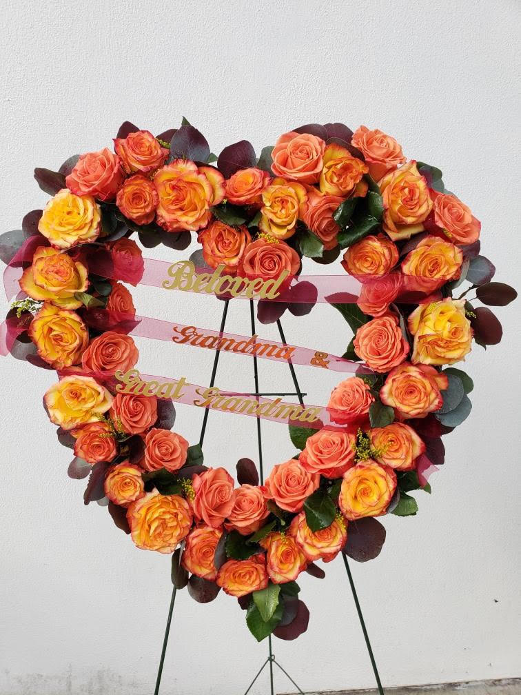 Heart-shaped rose wreath on a stand with pink ribbons