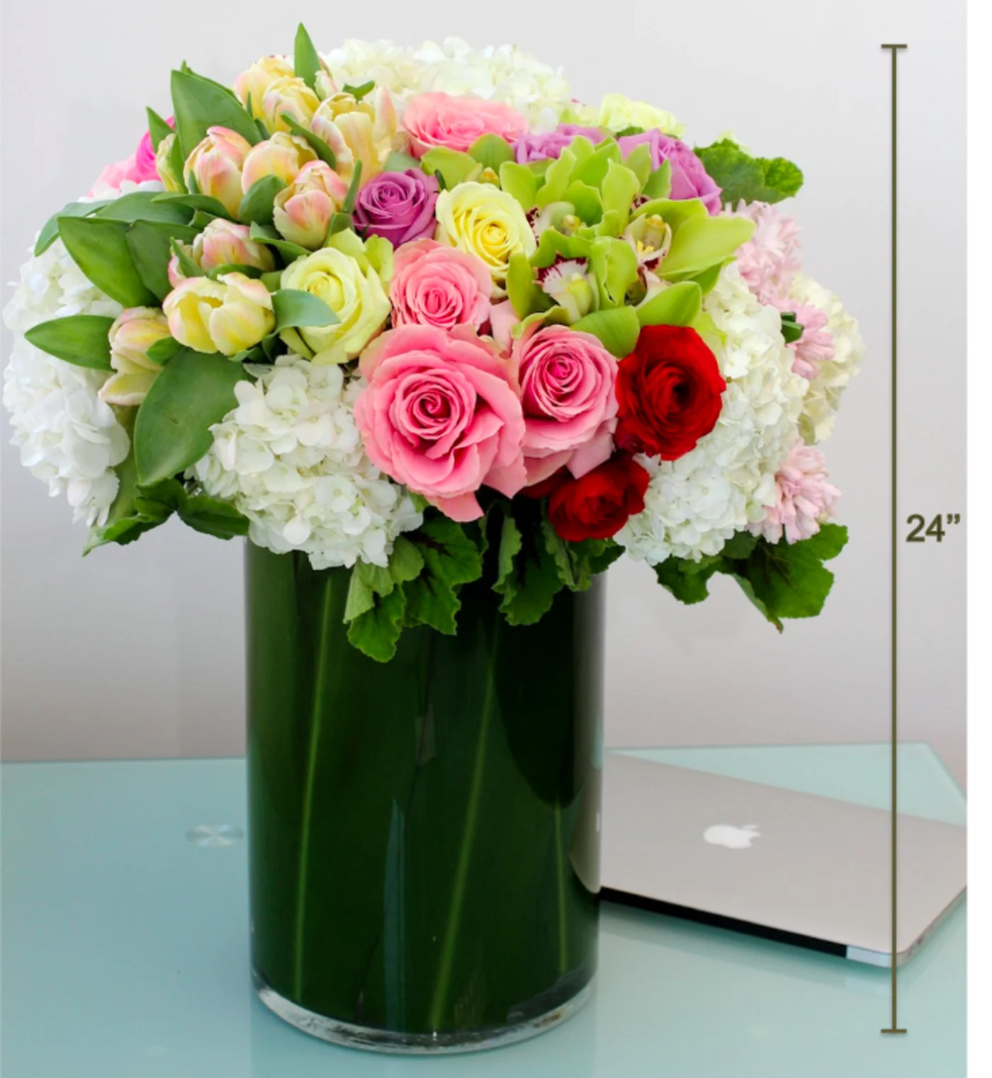 Mixed pink, white, and red roses in a tall green vase