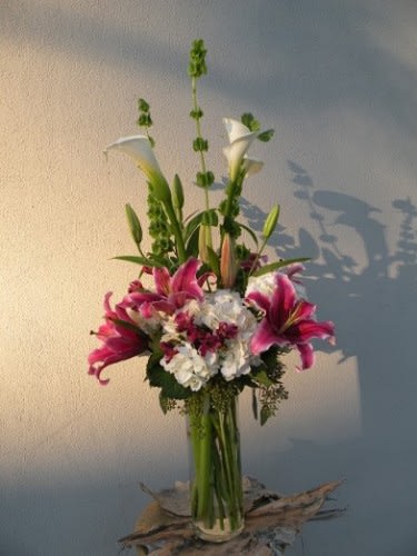 Tall bouquet of pink lilies and white flowers in a glass vase