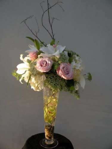 Pink roses and white lilies arranged in a tall glass vase