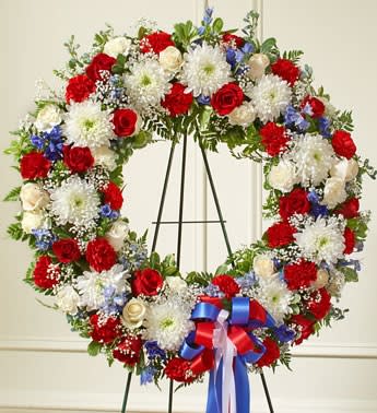 Large red, white, and blue floral wreath on an easel with ribbon