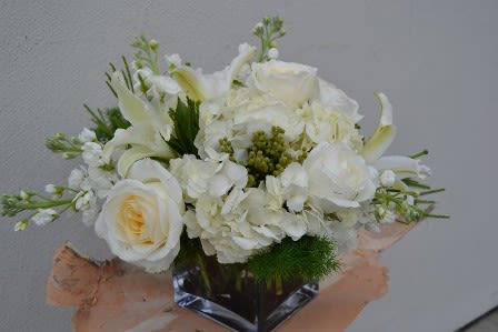 White floral bouquet with roses and lilies in a clear vase