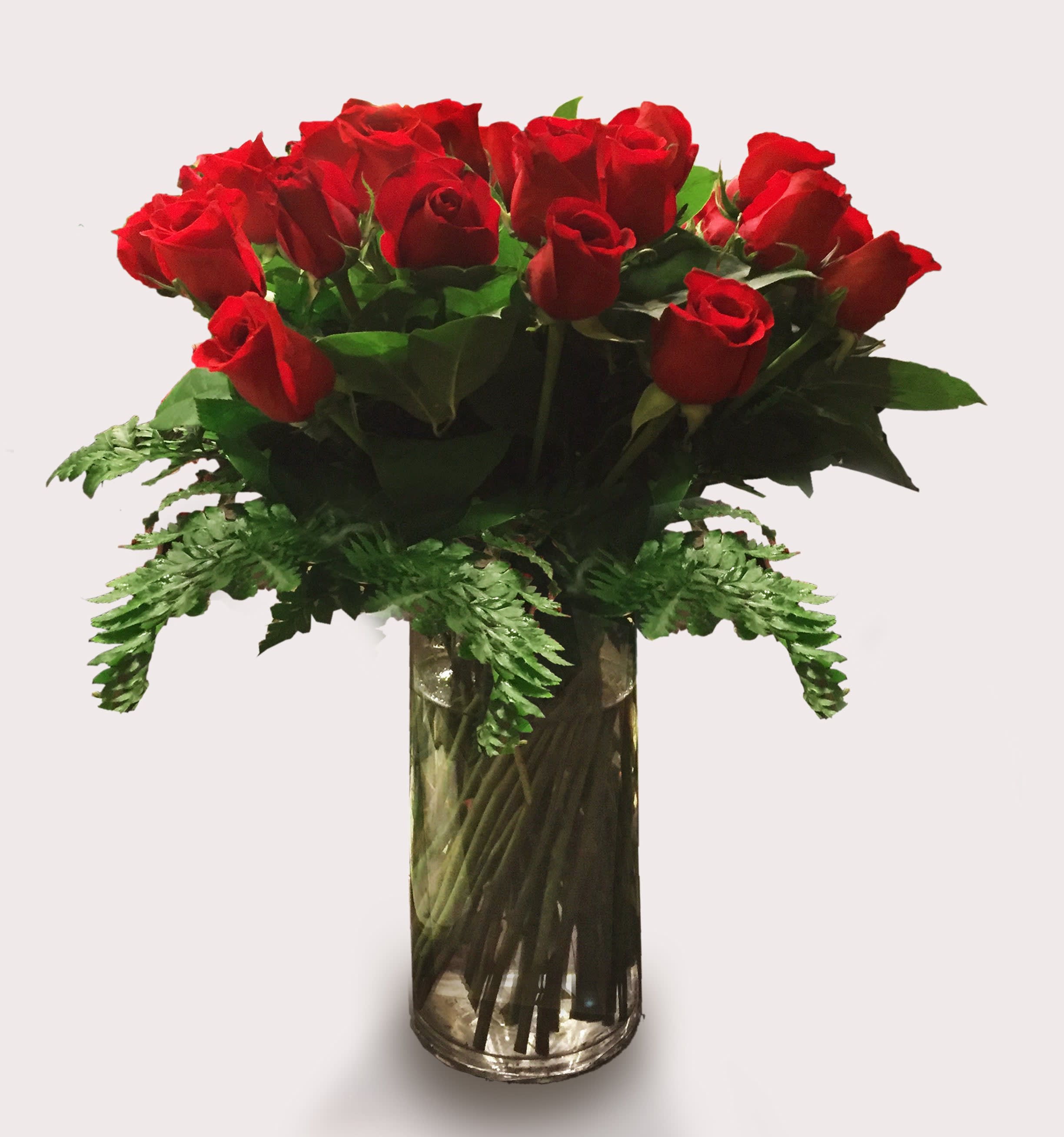 Red roses arranged in a clear glass vase with fern accents