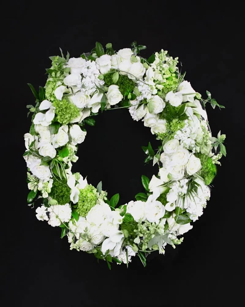 White floral wreath with roses and orchids on a black background