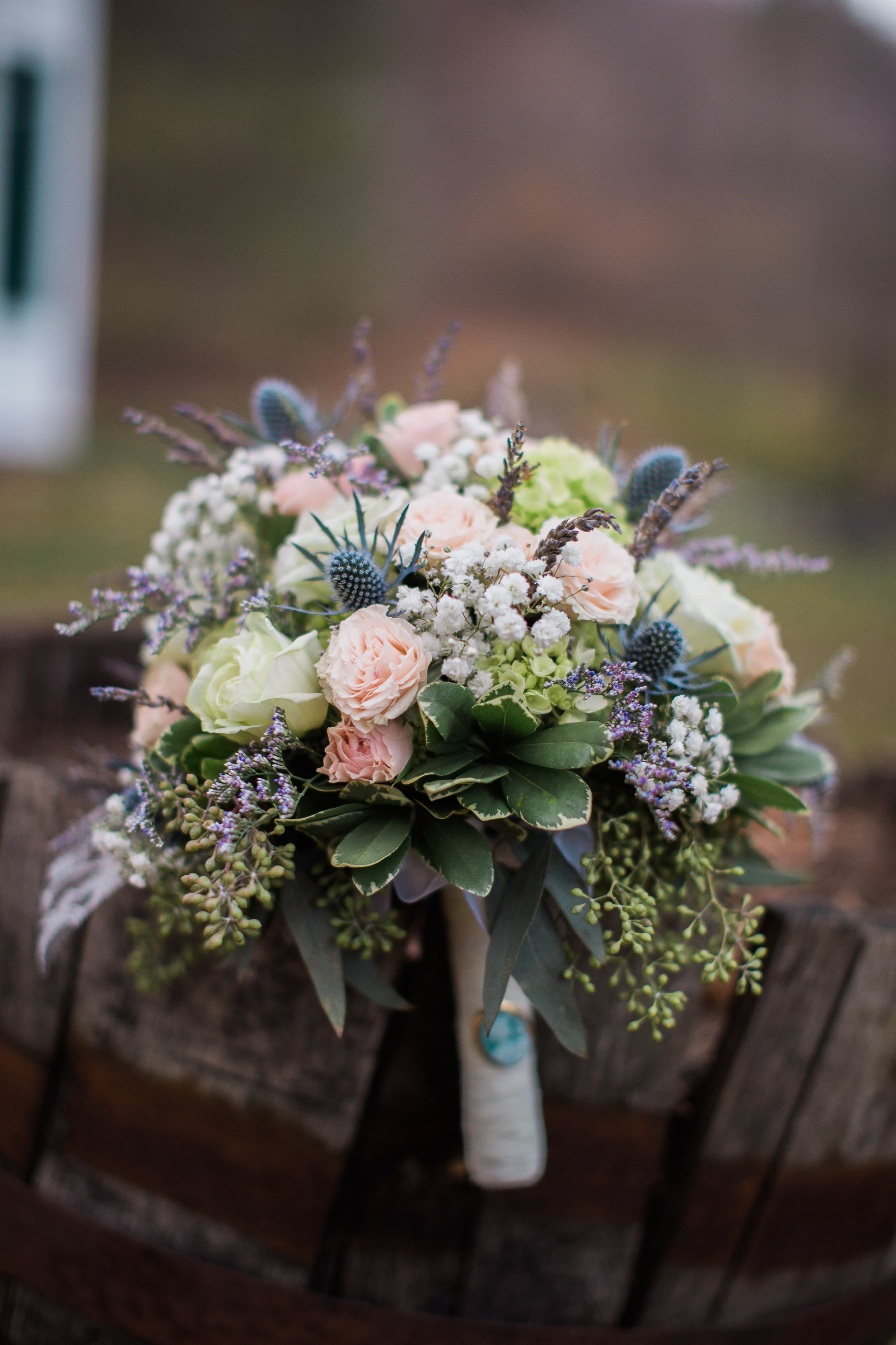 Bouquet of pale pink and white roses with blue thistle accents
